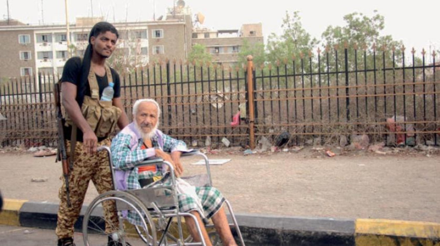 Government security member helps his disabled father get to a Mosque for Eid Prayers in Aden. EPA