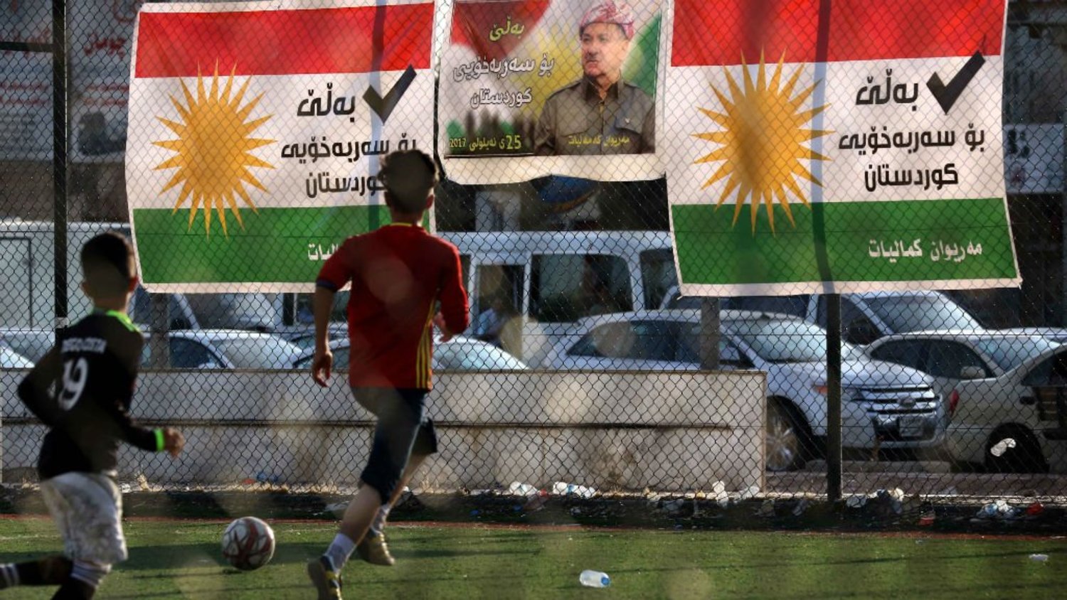 Iraqi Kurdish boys play football near referendum campaign posters of Iraqi Kurdish President Masoud Barzani in Irbil. (AFP)