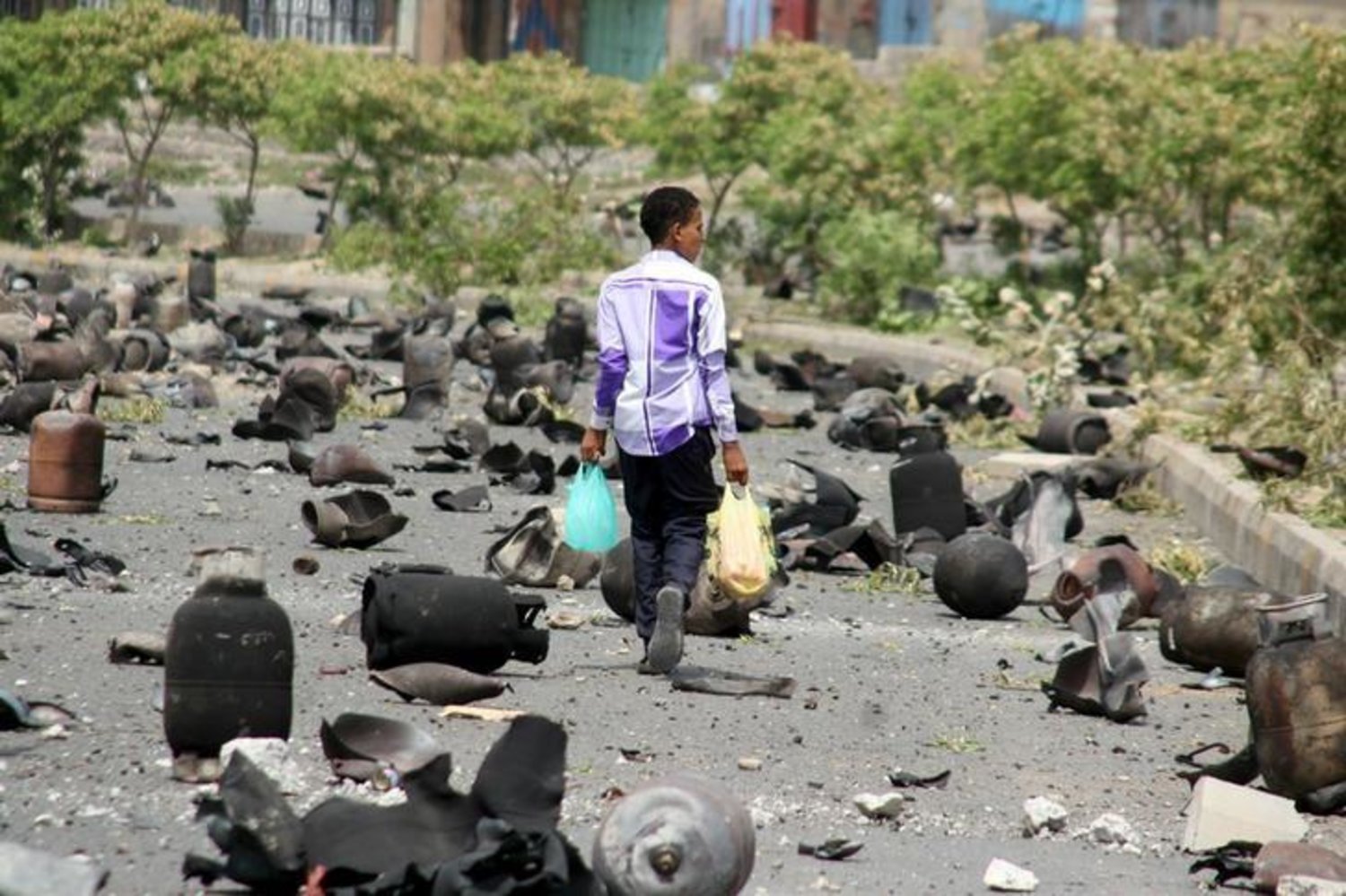 A boy walks on a street littered with cooking gas cylinders after a fire and explosions destroyed a nearby gas storage in Yemen's southwestern city of Taiz July 19, 2015. REUTERS/Stringer/Files
