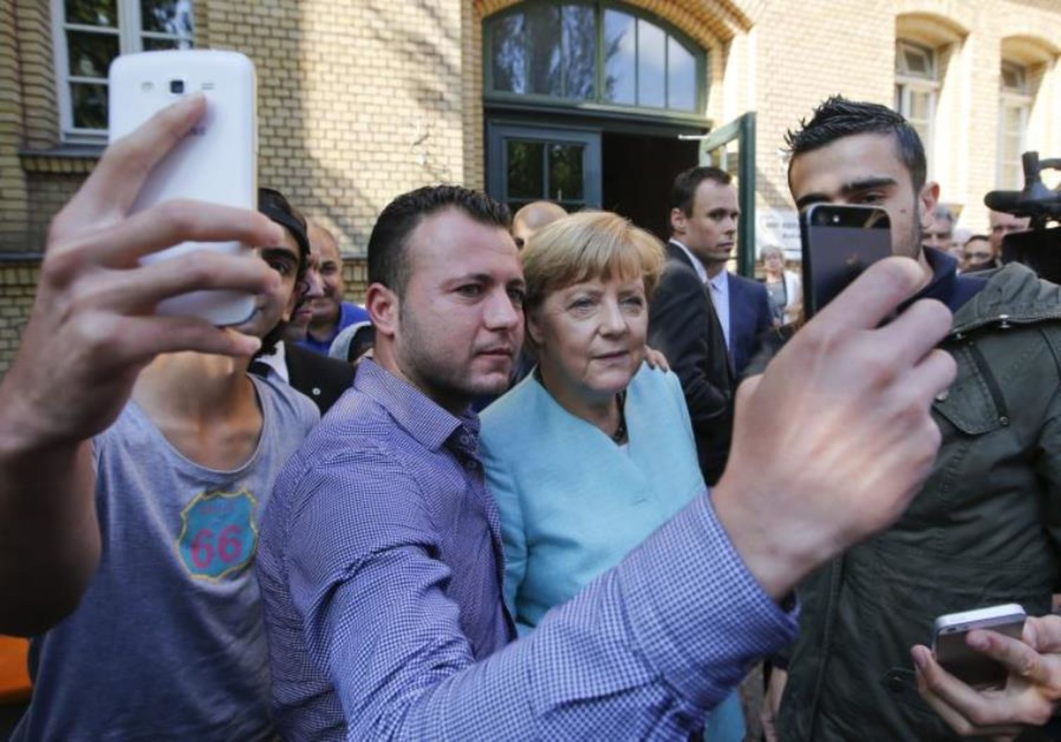 Migrants from Syria and Iraq take selfies with German Chancellor Angela Merkel outside a refugee camp near the Federal Office for Migration and Refugees after their registration at Berlin's Spandau district, Germany, September 10, 2015. Reuters