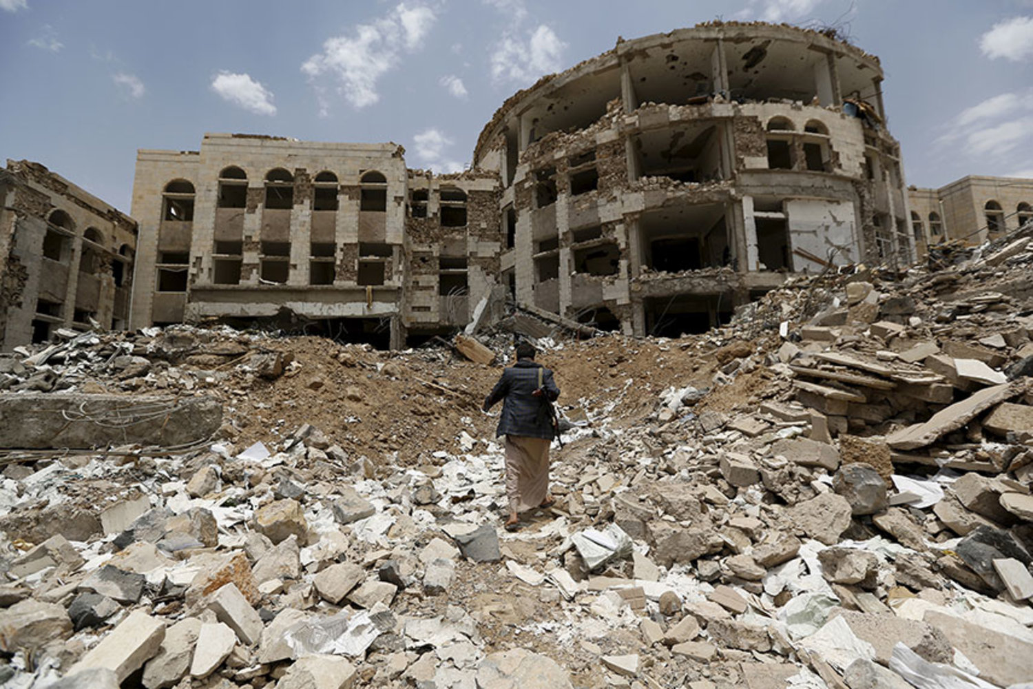 A Houthi militant walks through the rubble in Yemen. (Reuters)