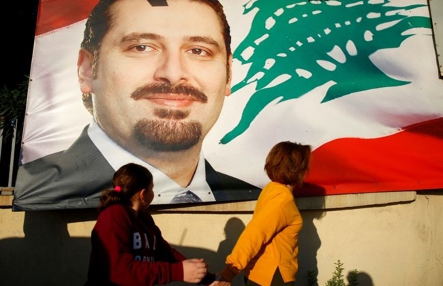 A woman and her daughter pass by a poster of outgoing Prime Minister Saad Hariri, in Beirut, Lebanon, Saturday, Nov. 11, 2017. (AP Photo/Hassan Ammar)