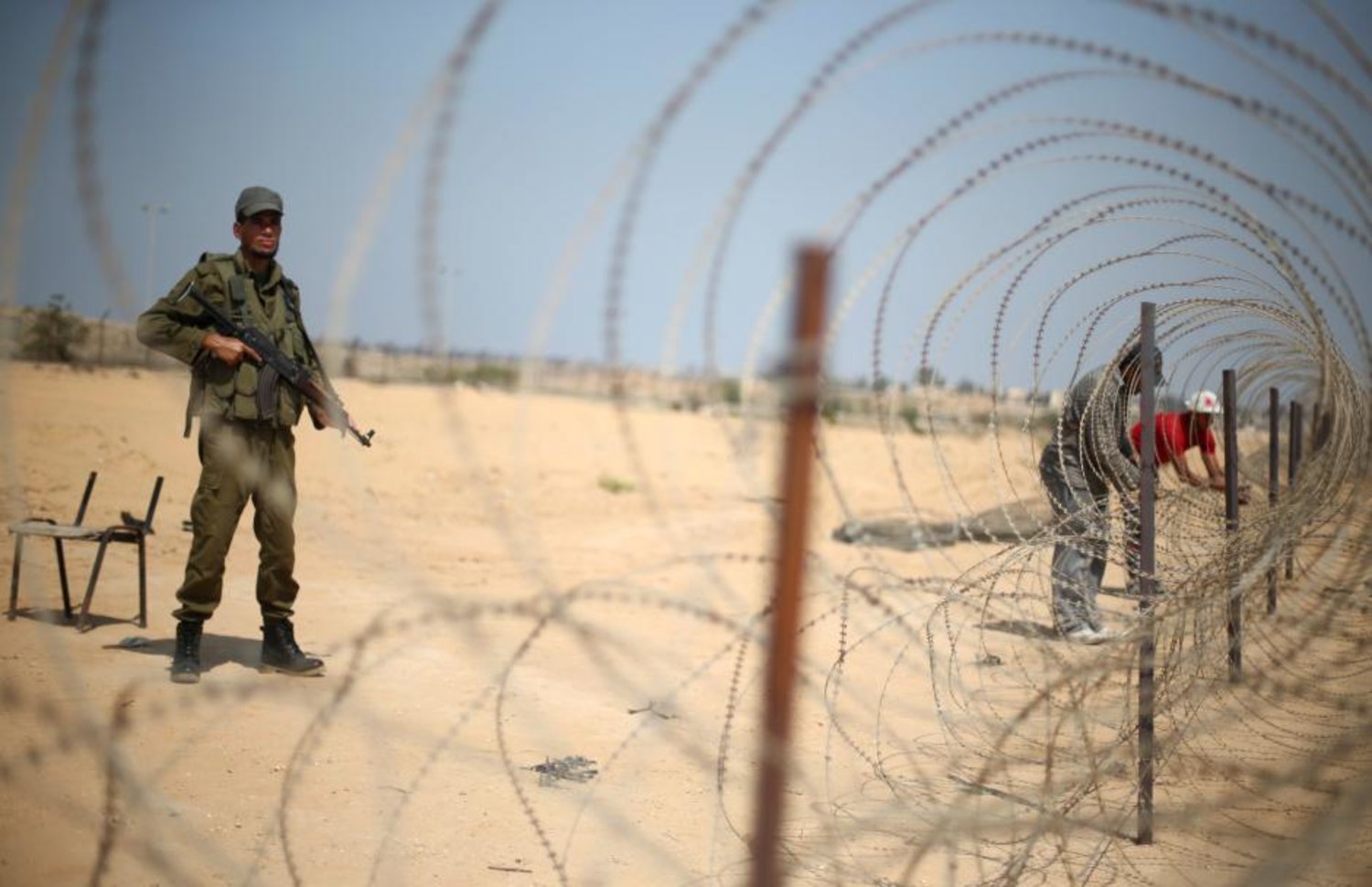 A member of the Palestinian security forces, loyal to Hamas, stands guard as men set up a barbed wire on the border with Egypt, in Rafah in the southern Gaza Strip, August 24, 2017. REUTERS/Ibraheem Abu Mustafa/File Photo