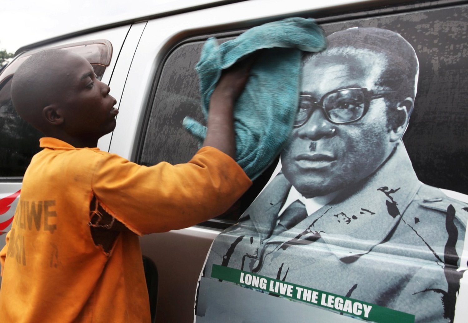 Youth washes a minibus adorned with picture of President Robert Mugabe at a bus terminus in Harare. (Reuters)