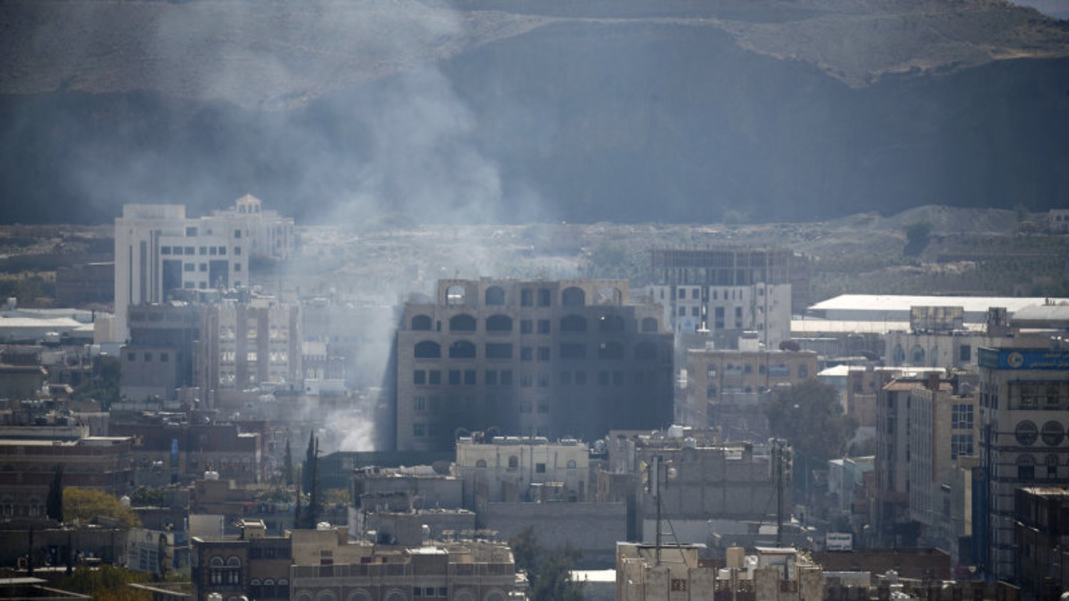 Smoke billows behind a building in the Yemeni capital Sana’a on Sunday, during clashes between Houthis and supporters of Yemeni ex-President Ali Abdullah Saleh. (AFP)