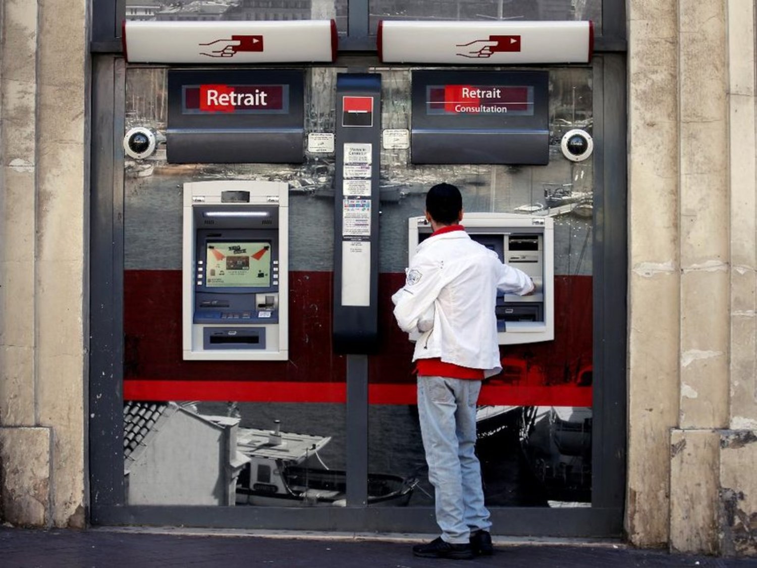A customer withdraws money from an ATM at a Societe Generale bank branch in Marseille, France, September 4, 2017. REUTERS/Jean-Paul Pelissier