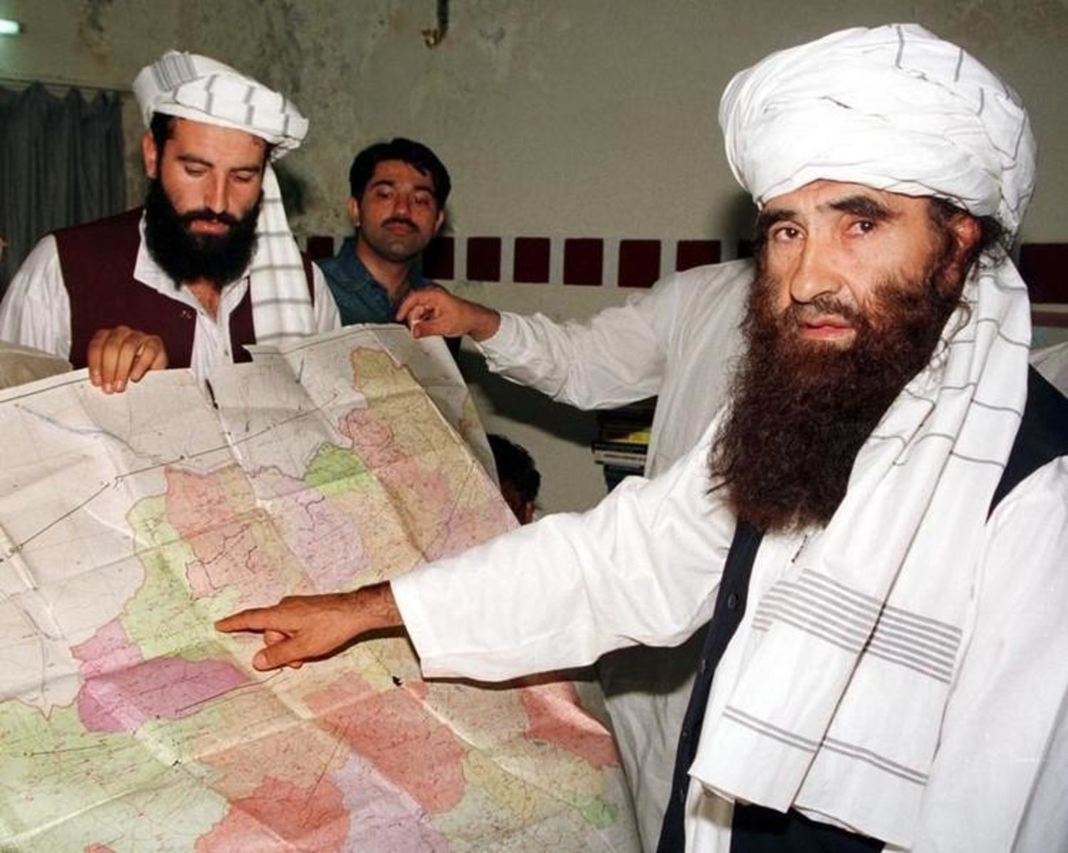 Jalaluddin Haqqani (R), the Taliban's Minister for Tribal Affairs, points to a map of Afghanistan during a visit to Islamabad, Pakistan while his son Naziruddin (L) looks on. (Reuters 2001 file photo)