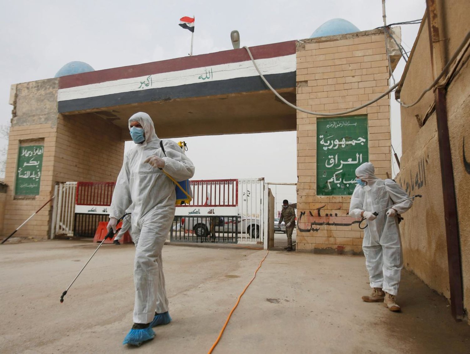Workers in protective suits spray disinfectants near the gate of Shalamcha Border Crossing, after Iraq shut a border crossing to travelers between Iraq and Iran (file photo: Reuters)