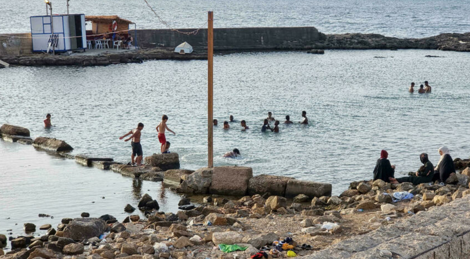 Libyans swim in the Mediterranean sea at the capital Tripoli's waterfront, on August 21, 2021. (Photo by Mahmud TURKIA / AFP)