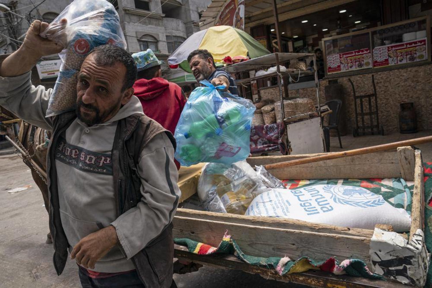 FILE - A bag of foodstuffs provided by the UN agency for Palestinian refugees (UNRWA) lies in a cart as Palestinians collect food aid following a cease-fire reached after an 11-day war between Gaza's Hamas rulers and Israel, in Gaza City, May 22, 2021.  (AP Photo/John Minchillo, File)

