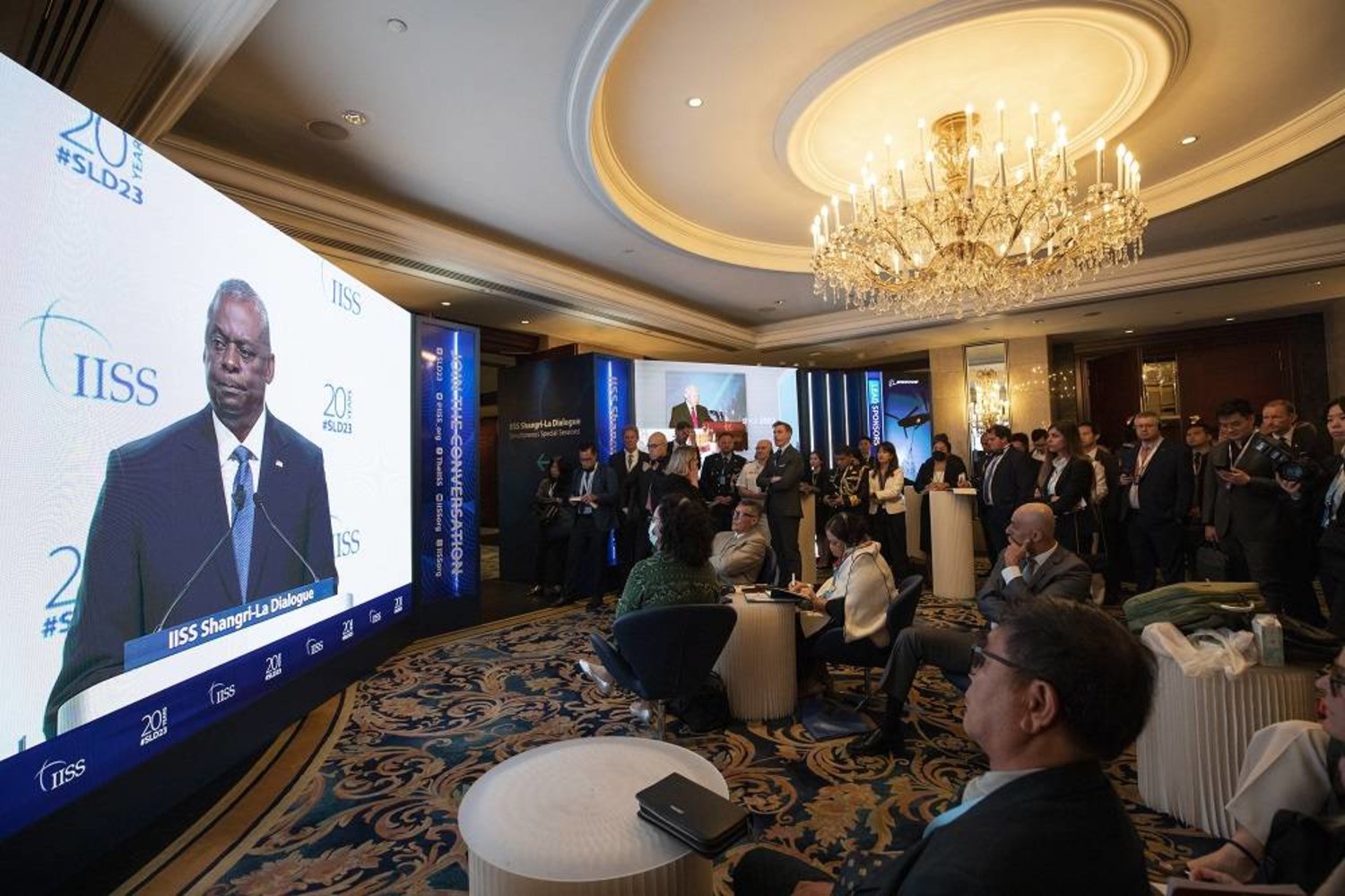 Attendees watch a livestream of US Secretary of Defense Lloyd Austin speaking during a plenary session on a screen outside the main hall during the International Institute for Strategic Studies (IISS) Shangri-La Dialogue at the Shangri-La hotel in Singapore, 03 June 2023. (EPA) 