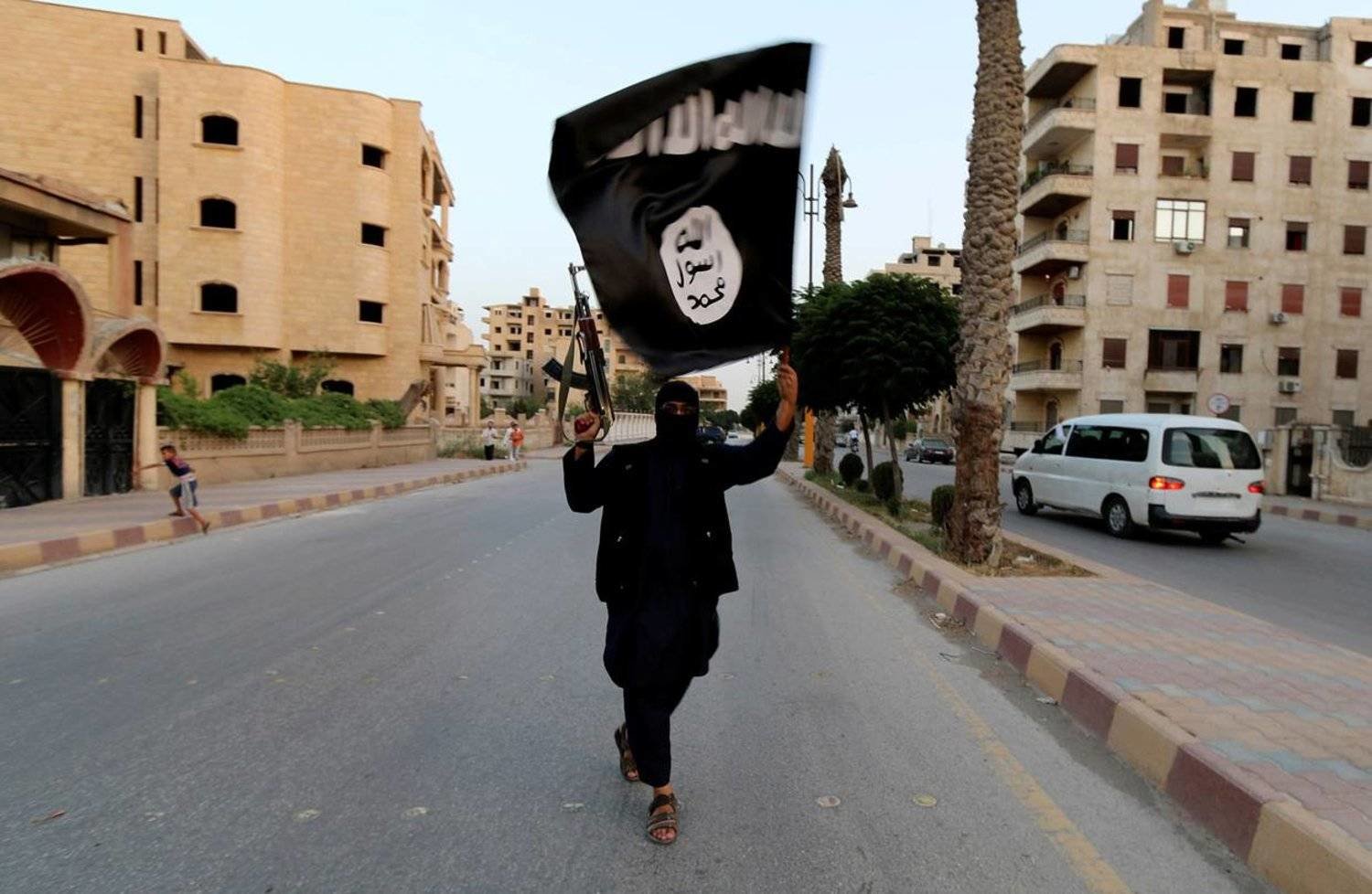 A member loyal to ISIS waves a flag in Raqqa, Syria June 29, 2014. REUTERS/Stringer/File Photo
