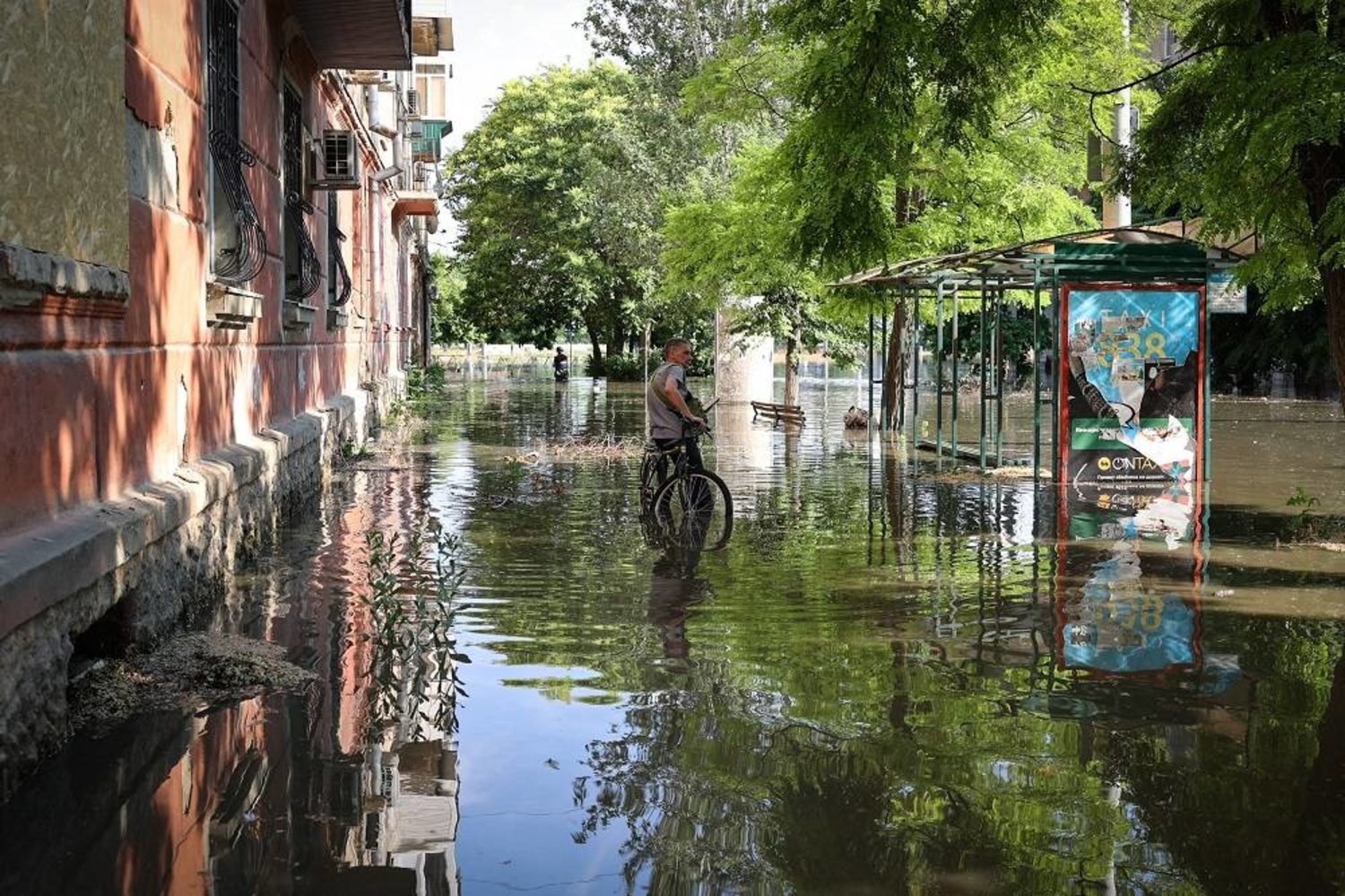 A local resident stands with his bicycle in a flooded street in the town of Kherson, following flooding caused by damage sustained at the Kakhovka HPP dam, on June 6, 2023. (AFP)