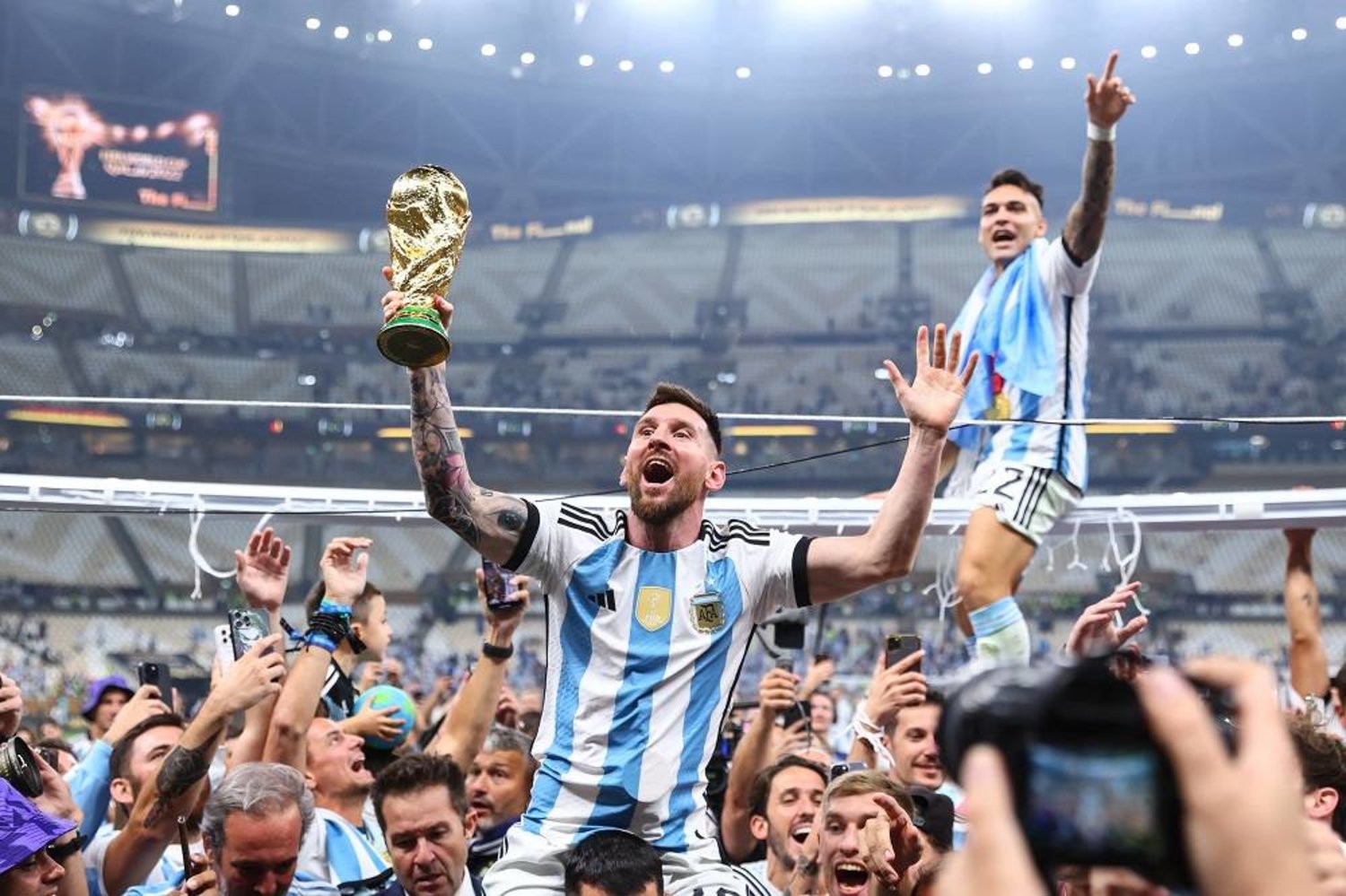 18 December 2022, Qatar, Lusail: Argentina's Lionel Messi (L) and Lautaro Martinez celebrate with the World Cup trophy after Argentina's victory in the FIFA World Cup Qatar 2022 final soccer match against France at the Lusail Stadium. (dpa)