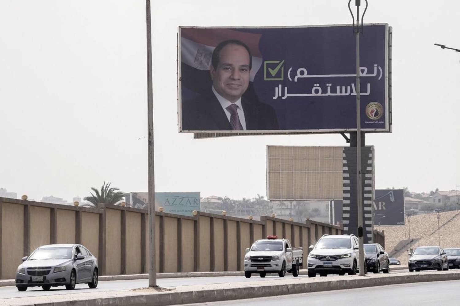 Vehicles pass under a billboard supporting Egyptian President Abdel Fattah al-Sisi for the coming presidential elections, erected by Egypt's political party of Homat Watan, the Protectors of the Nation, in Cairo, Egypt, on Sept. 4, 2023. (AP)