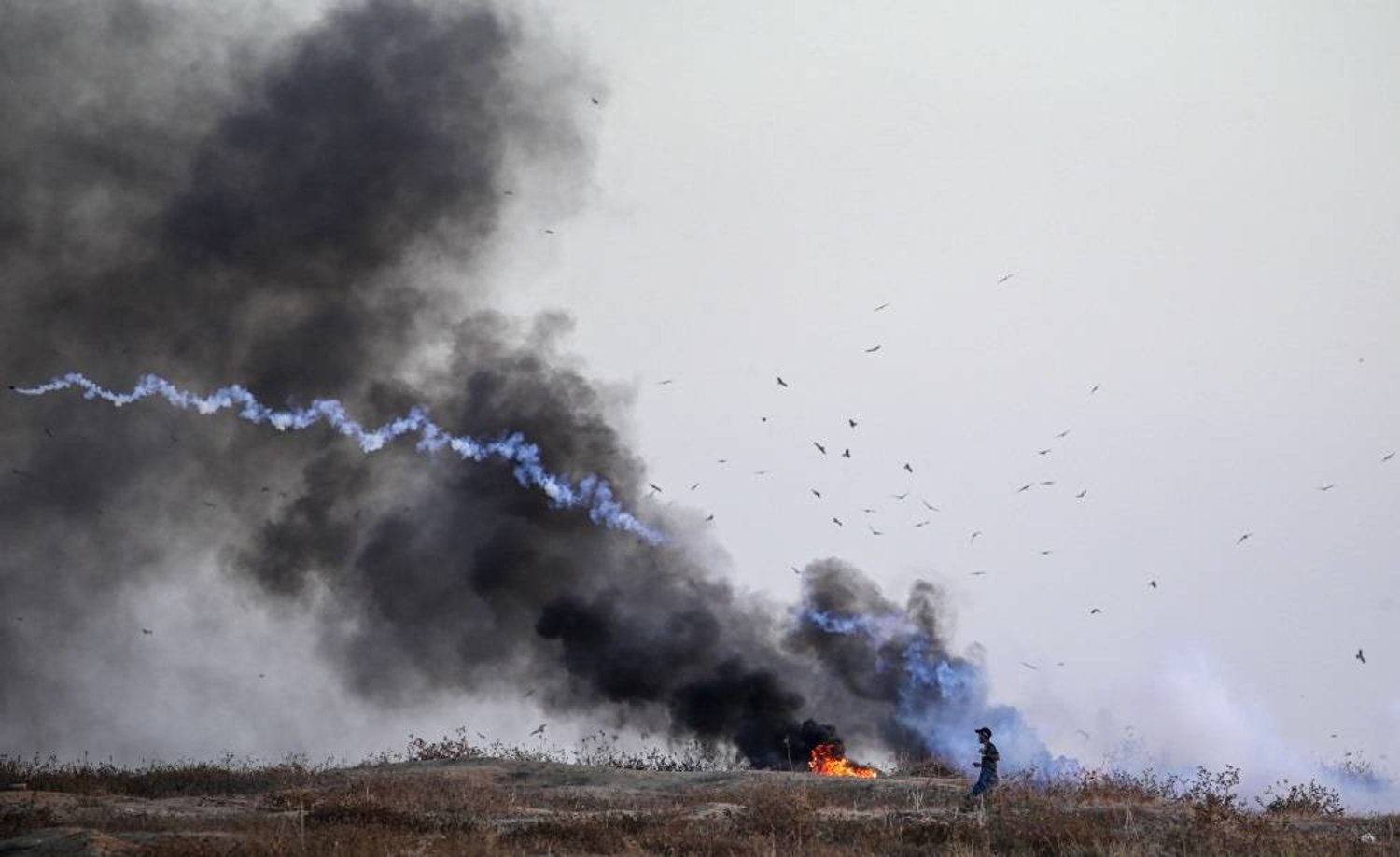 A Palestinian protester throws a tear gas canister back during clashes with Israeli troops on the eastern border of the Gaza Strip, 26 September 2023. (EPA)
