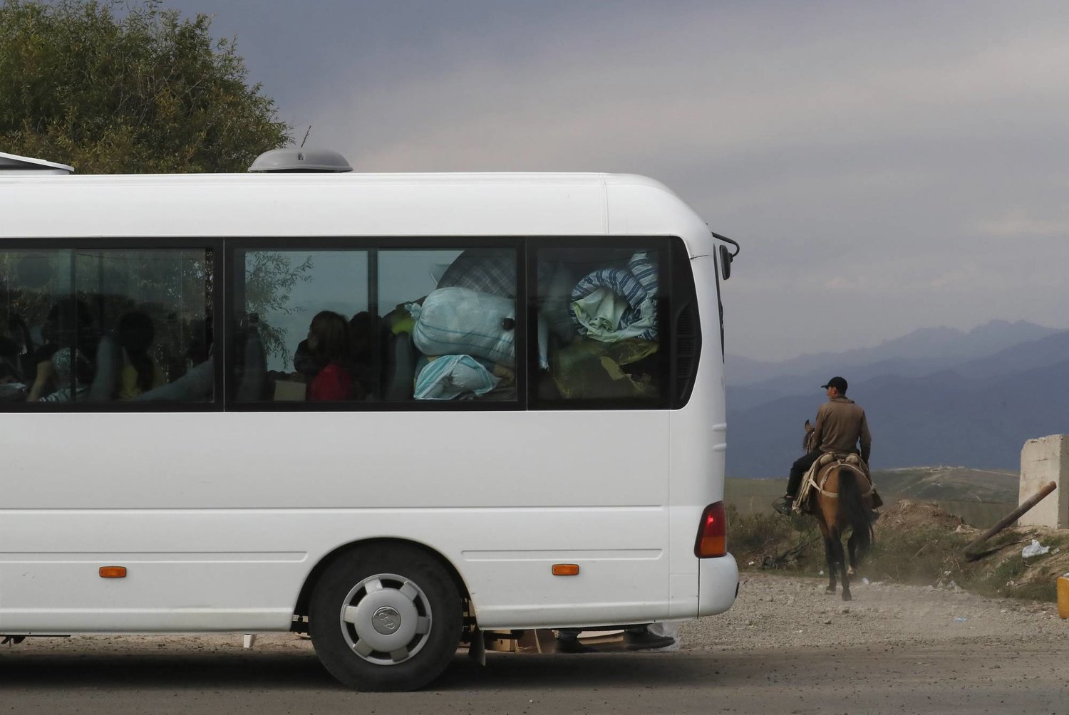 A local rides a horse (R, back) as ethnic Armenians from Nagorno-Karabakh cross the border with Azerbaijan on a bus with their belongings, near the village of Kornidzor, Armenia, 29 September 2023. EPA/ANATOLY MALTSEV