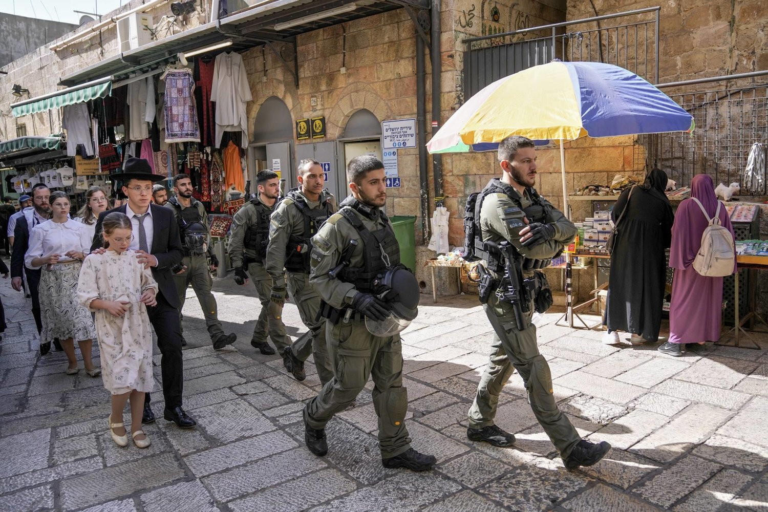 Jewish worshippers walk alongside Israeli border police officers during the Jewish holiday of Sukkot, in Jerusalem's Old City, Saturday, Sept. 30, 2023. (AP Photo/Mahmoud Illean)