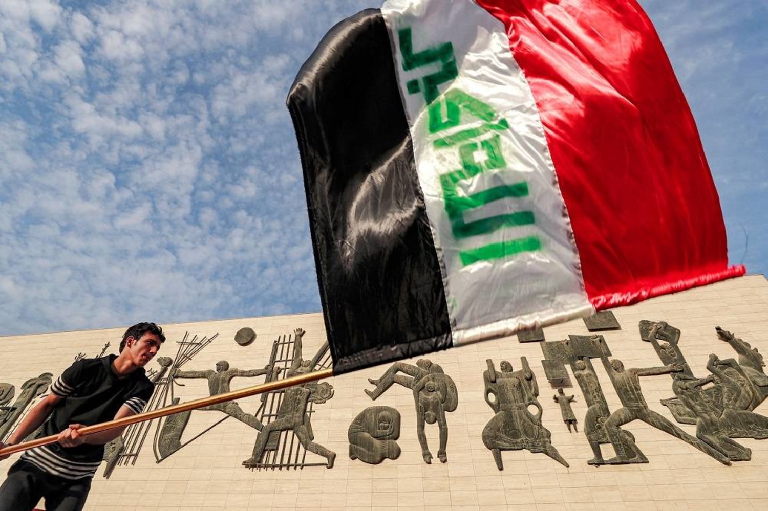 A man waves an Iraqi national flag as protesters gather in Baghdad's Tahrir square to mark the 4th anniversary of the 2019 anti-government demonstrations on October 1, 2023. (AFP)