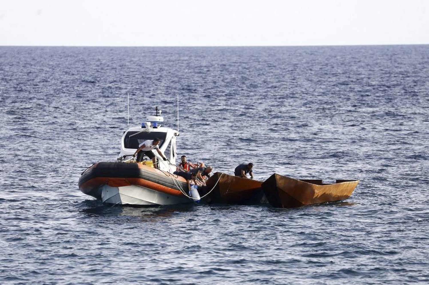 Italian Coast Guard personnel prepare to tow boats used to carry migrants, near the port of the Sicilian island of Lampedusa, southern Italy, Monday, Sept. 18, 2023. (LaPresse via AP))