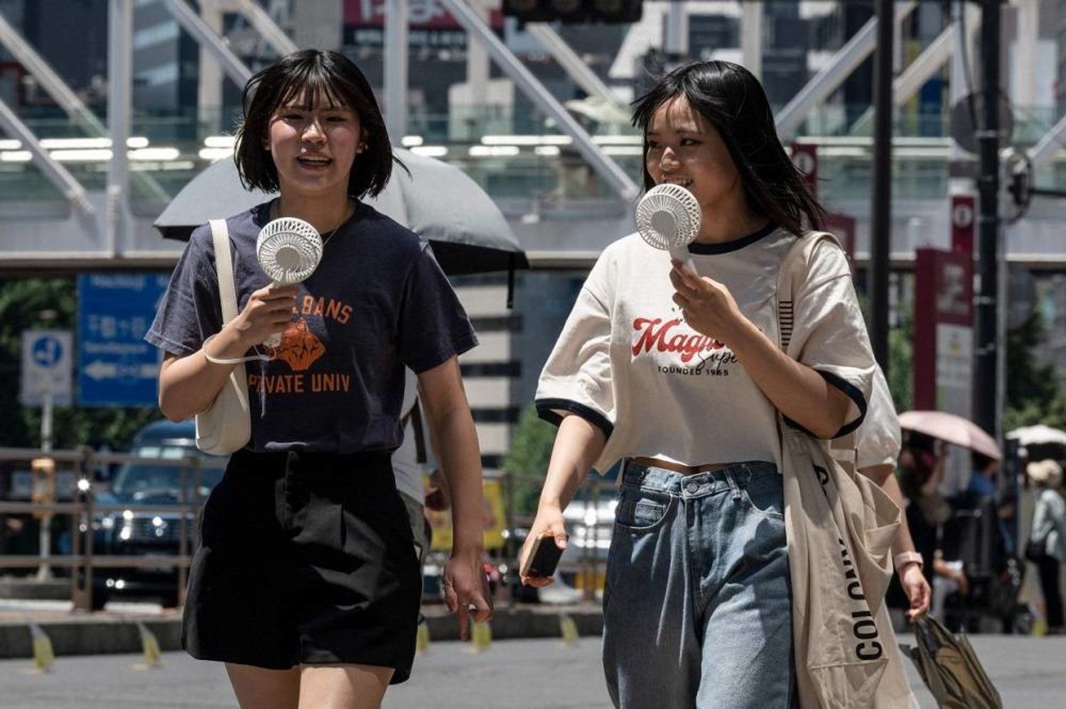 Young women use portable fans to seek relief from the heat as temperatures soar in Japan. (AFP)