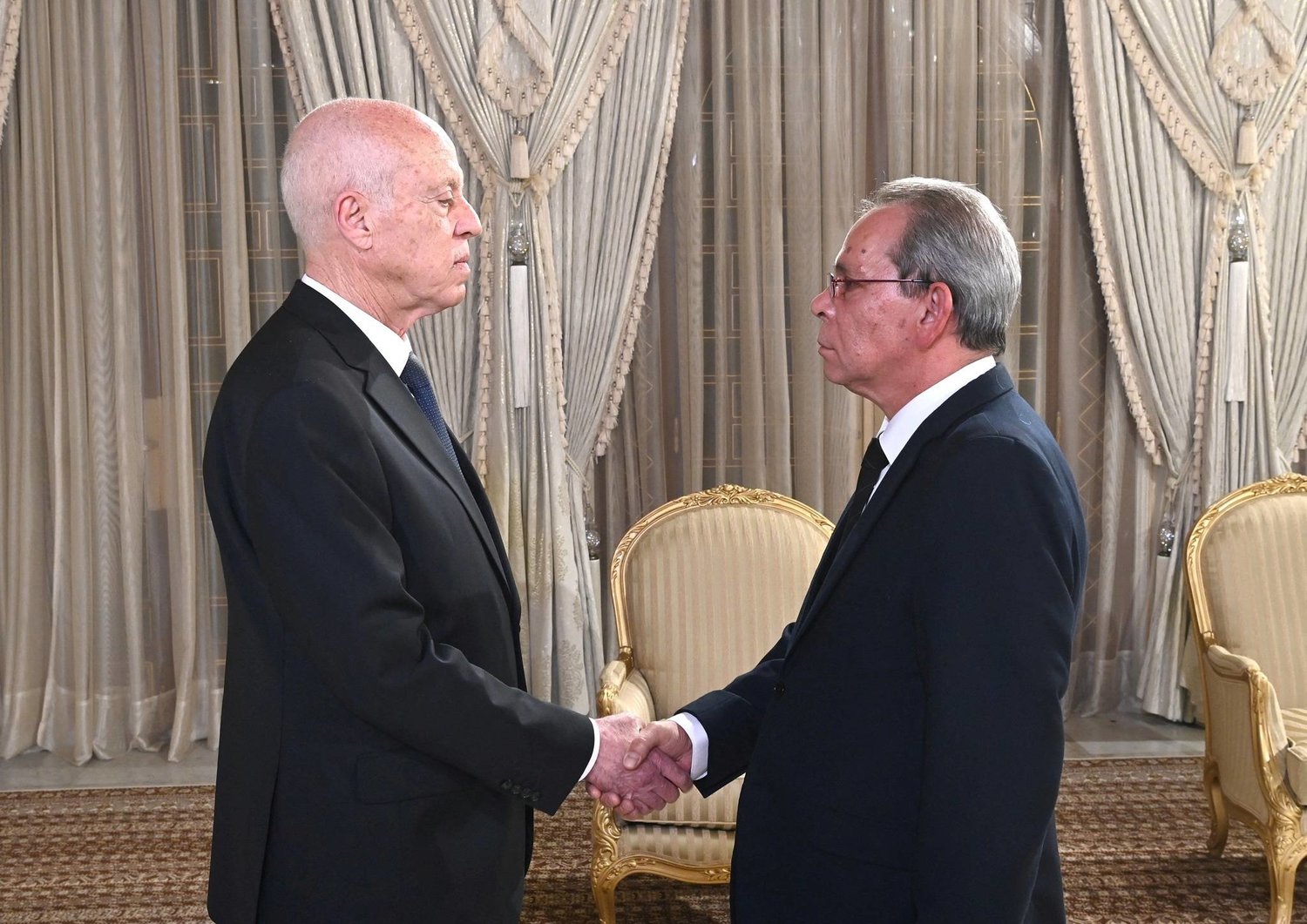 Tunisia's President Kais Saied shakes hands with newly appointed Tunisian Prime Minister Ahmed Hachani, in Tunis, Tunisia August 1, 2023. (Tunisian Presidency/Handout via Reuters)