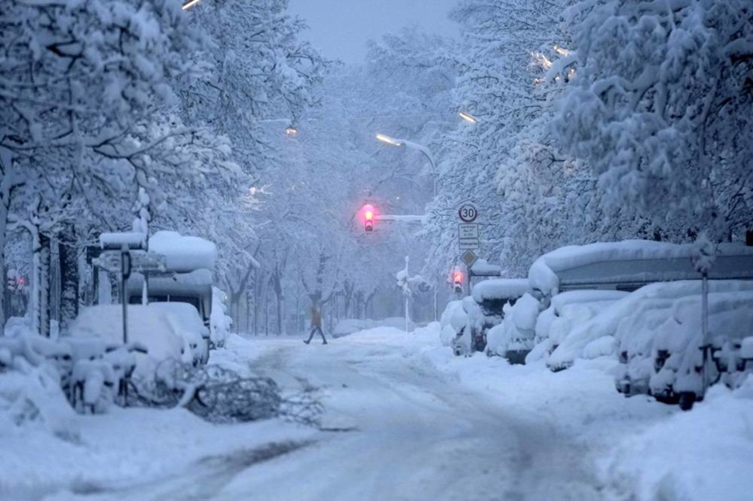 A man crosses a road early morning after heavy snow fall in Munich, Germany, Saturday, Dec. 2, 2023. (AP)