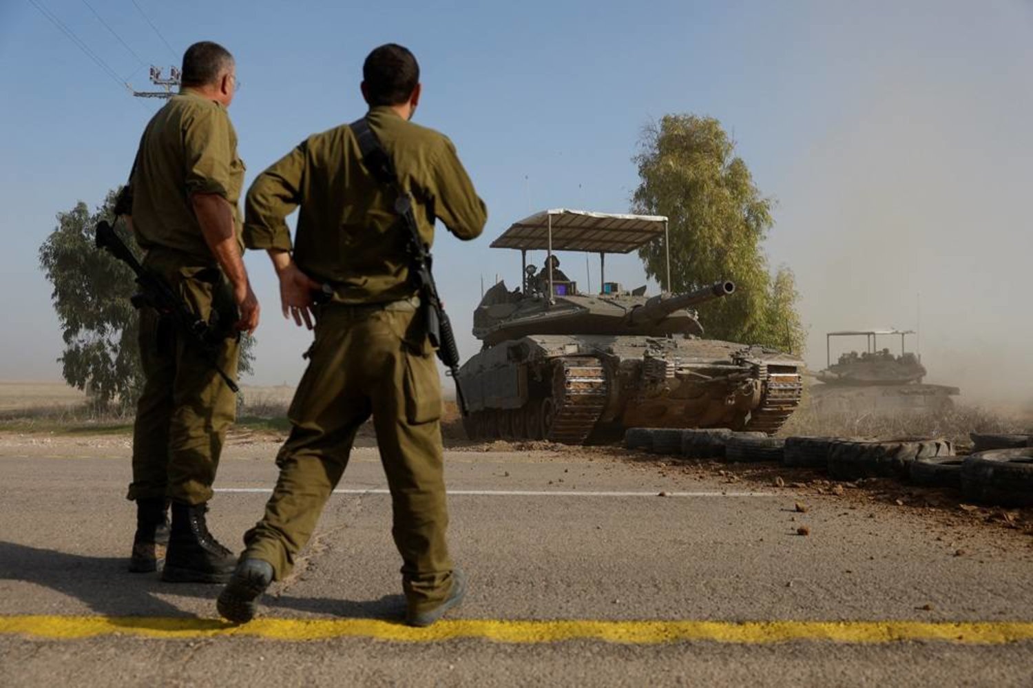  Israeli soldiers watch a tank cross a road, amid the ongoing conflict between Israel and the Palestinian group Hamas, near Israel's border with southern Gaza, in Israel, December 4, 2023. (Reuters)