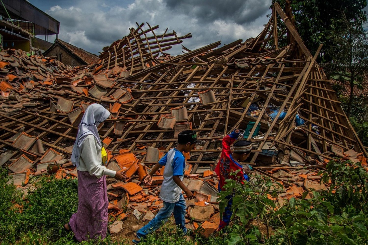 Children walk past a house that collapsed in an earthquake, Cianjur, West Java, Indonesia, Dec. 1, 2022. (AFP)