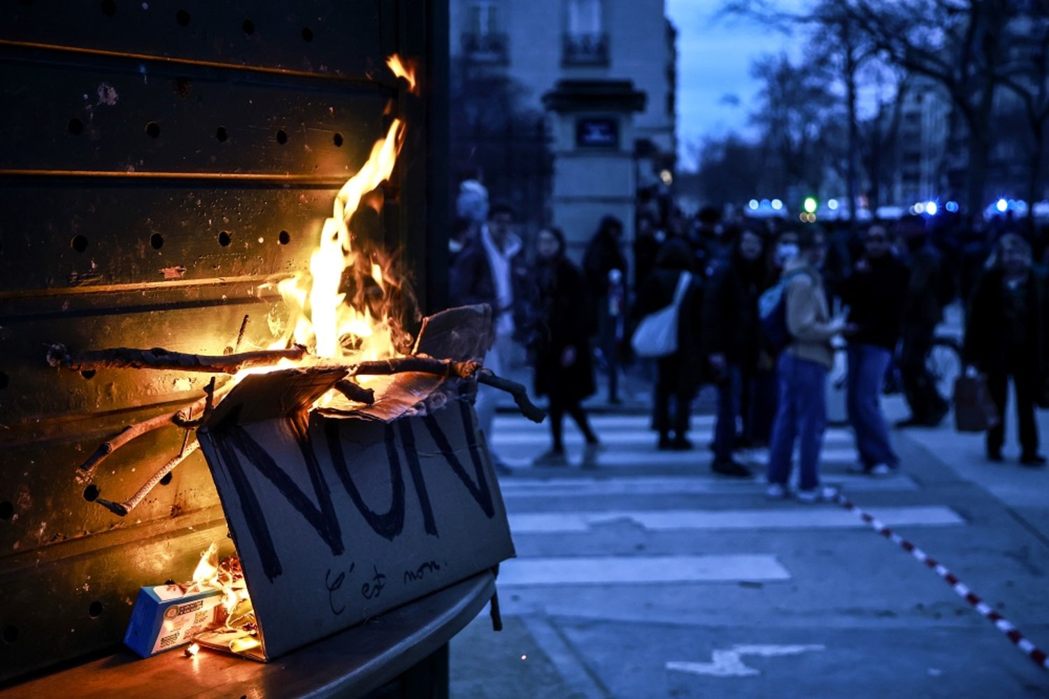 A placard that reads "No" burns during a demonstration against the government pension reform at Vauban square in Paris, France, 20 March 2023. (EPA)