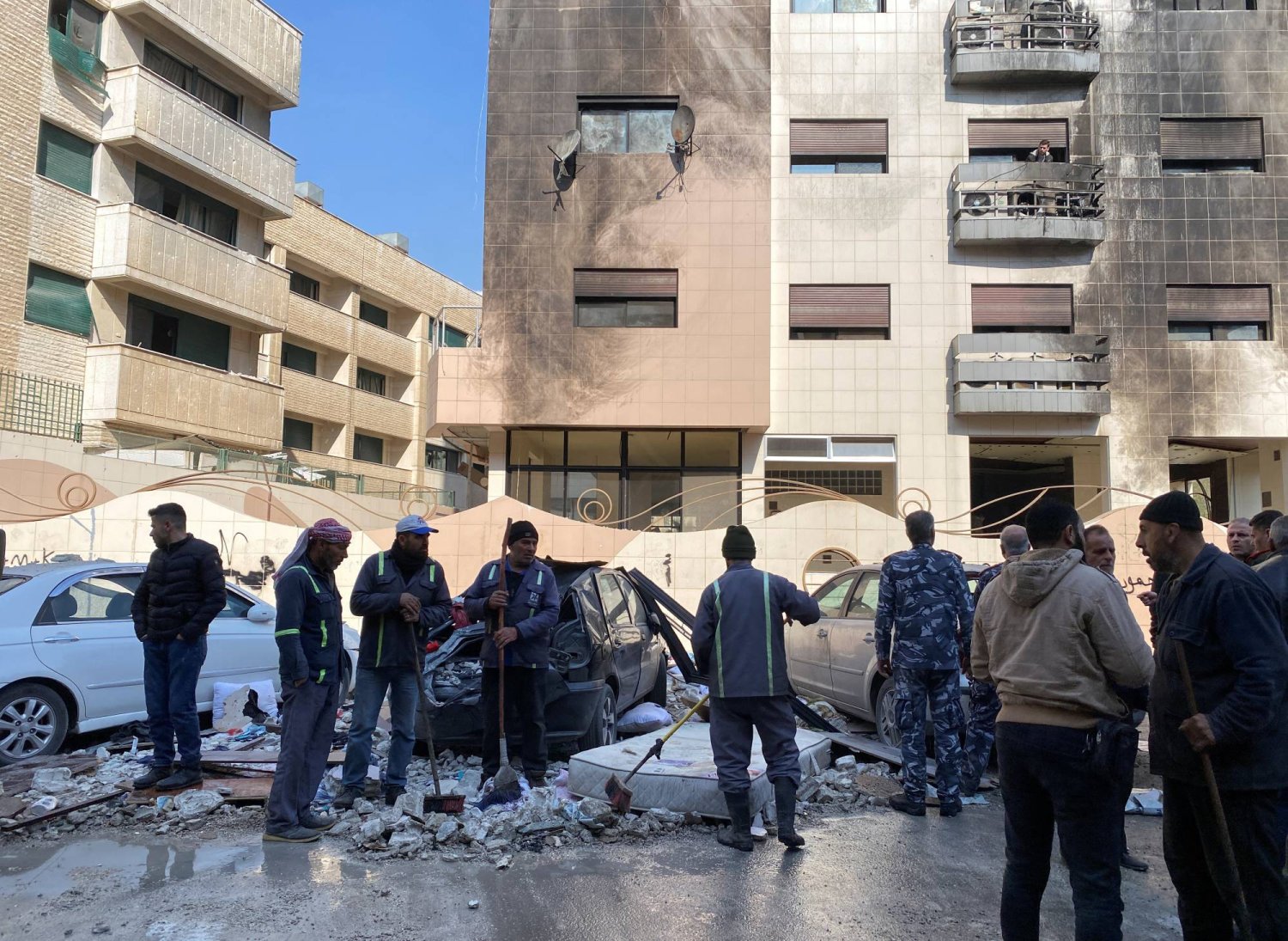 Workers and people stand near a damaged building after, according to Syrian state media reports, several Israeli missiles hit a residential building in the Kafr Sousa district, Damascus, Syria  February 21, 2024. REUTERS/Firas Makdesi