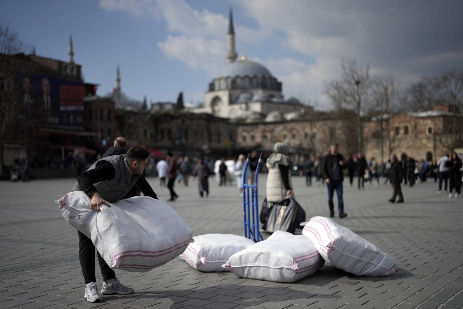 A man carries sacks of goods at Eminonu commercial area in Istanbul, Türkiye, Wednesday, Feb. 21, 2024. (AP Photo/Khalil Hamra)