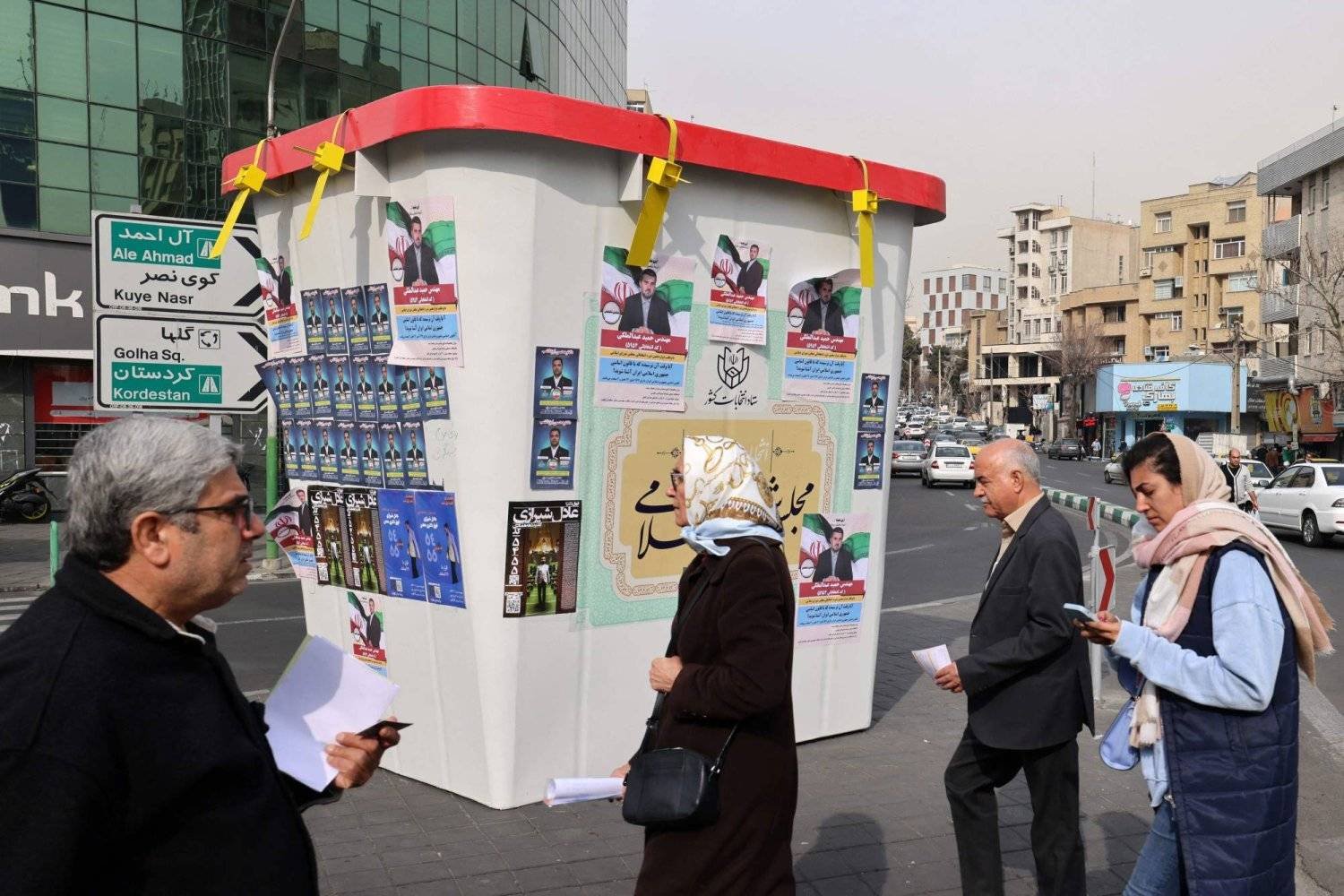 Iranians pass by a booth displaying campaign posters on Saturday (AFP)