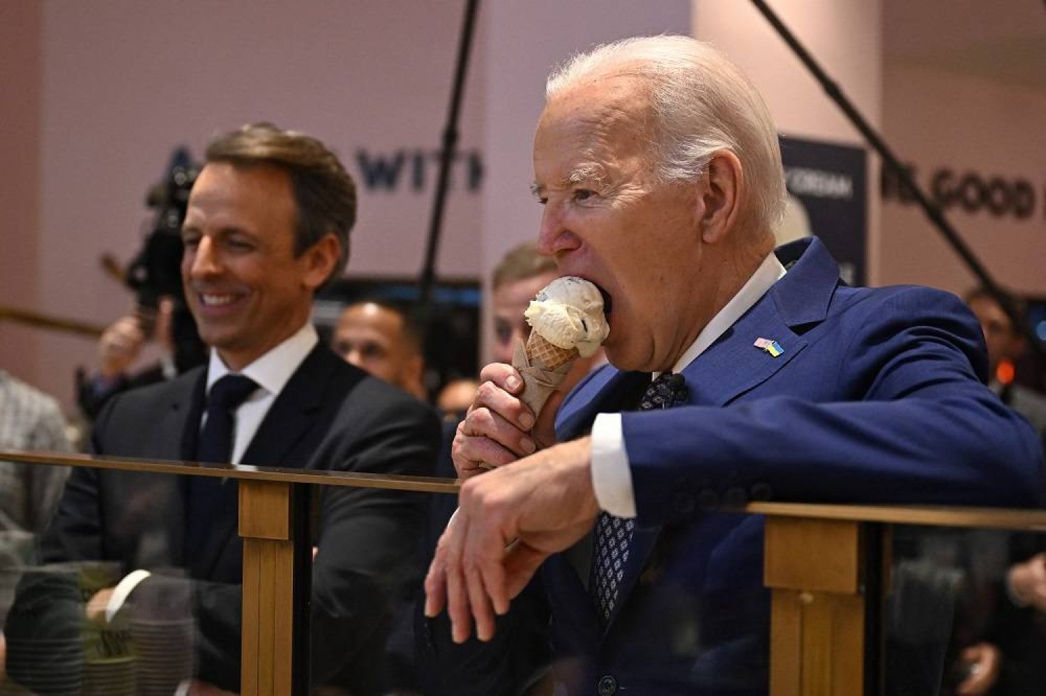 US President Joe Biden (R), flanked by host Seth Meyers (L), eats an ice cream cone at Van Leeuwen Ice Cream after taping an episode of "Late Night with Seth Meyers" in New York City on February 26, 2024. (AFP)
