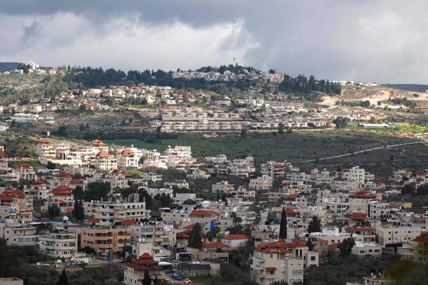 A picture taken in the village of Turmus Ayya near Ramallah city shows the nearby Israeli Shilo settlement in the background, in the occupied West Bank on February 18, 2024. (Photo by Jaafar ASHTIYEH / AFP)
