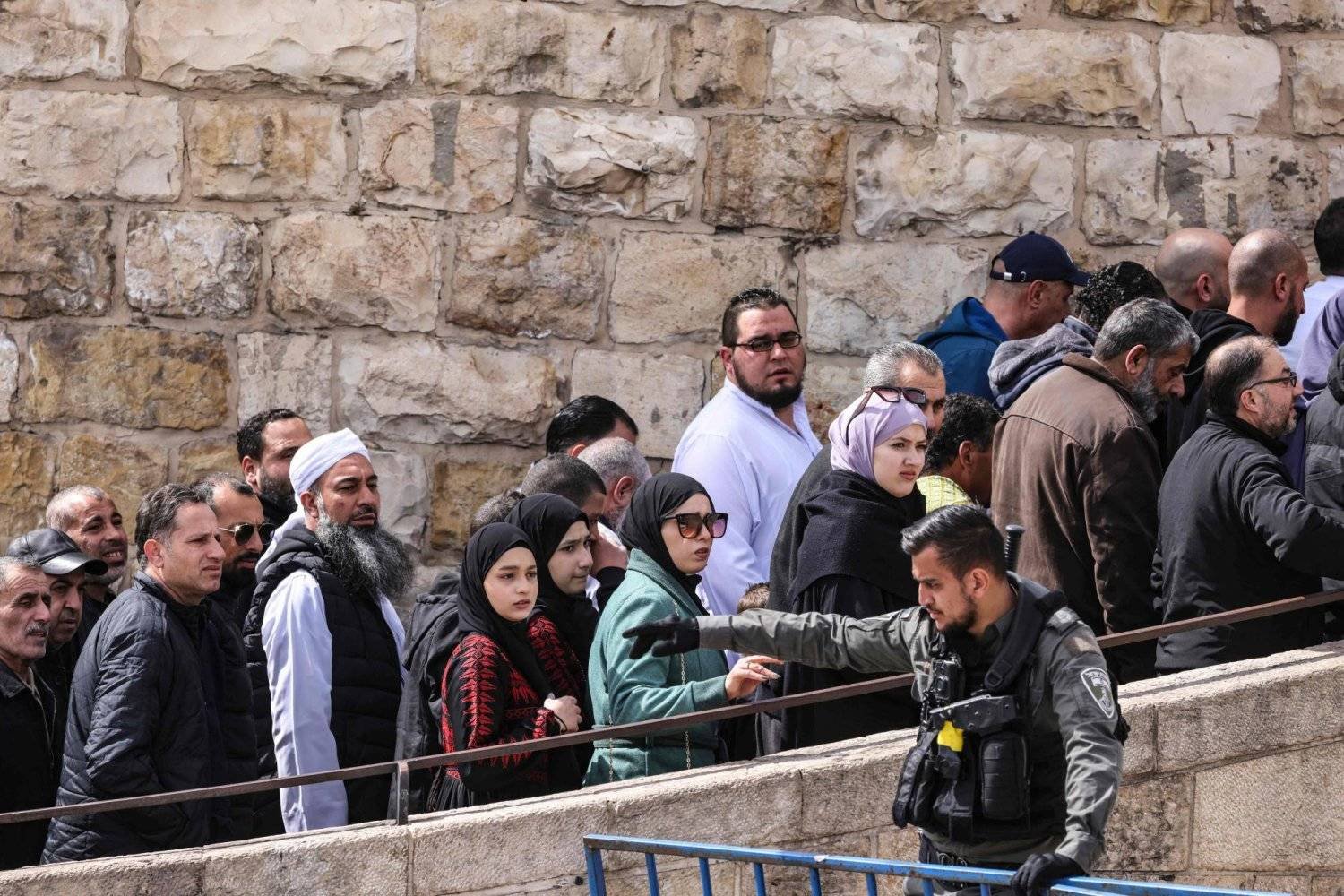 An Israeli security officer stands guard as Muslim worshipers pass through a checkpoint near the Asbat Gate in Jerusalem to enter the Al-Aqsa Mosque compound for Friday prayers 