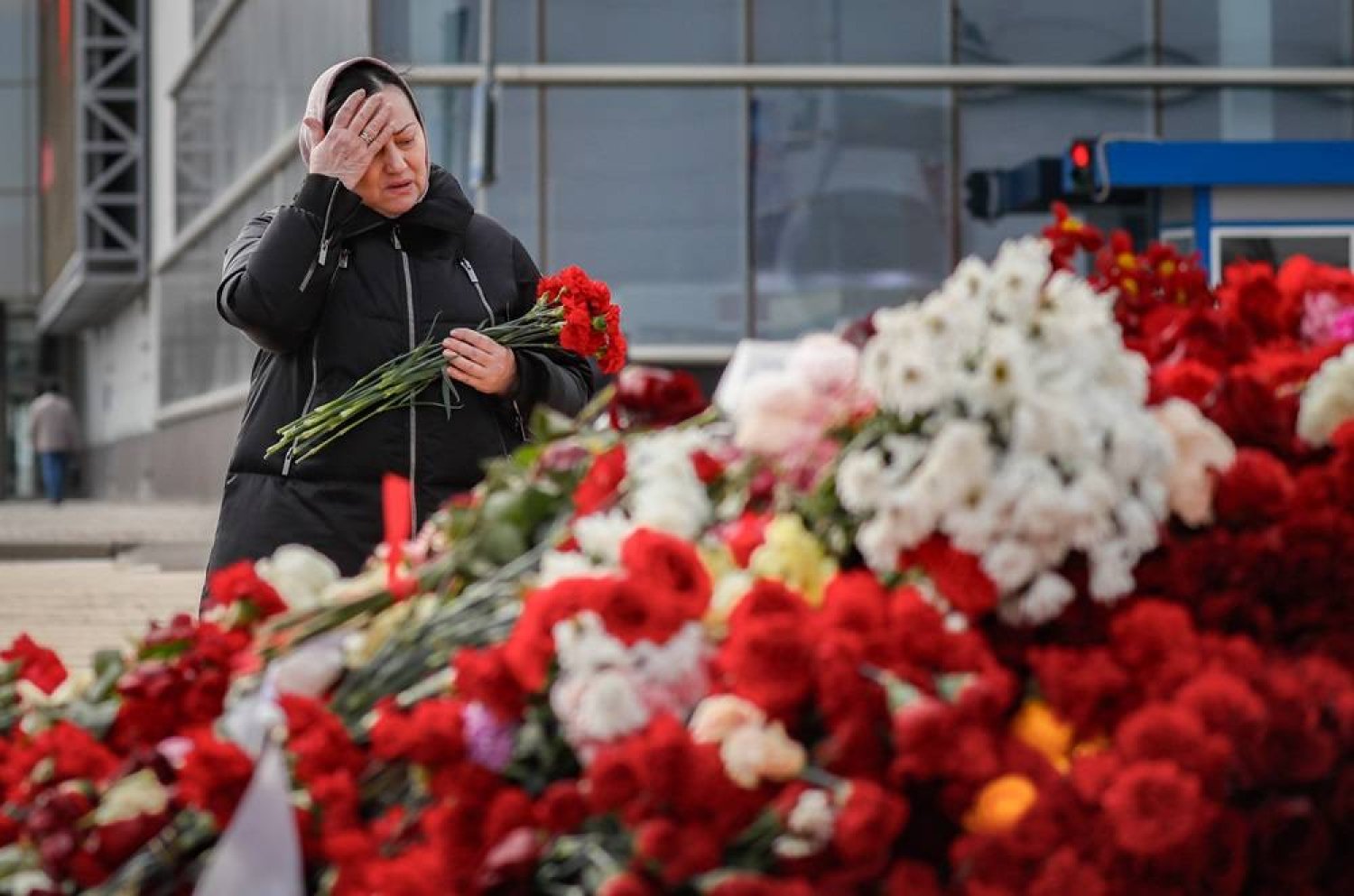 A Russian woman mourns and places flowers at the Crocus City Hall concert venue, six days after a terrorist attack in Krasnogorsk, outside Moscow, Russia, 28 March 2024. (EPA)