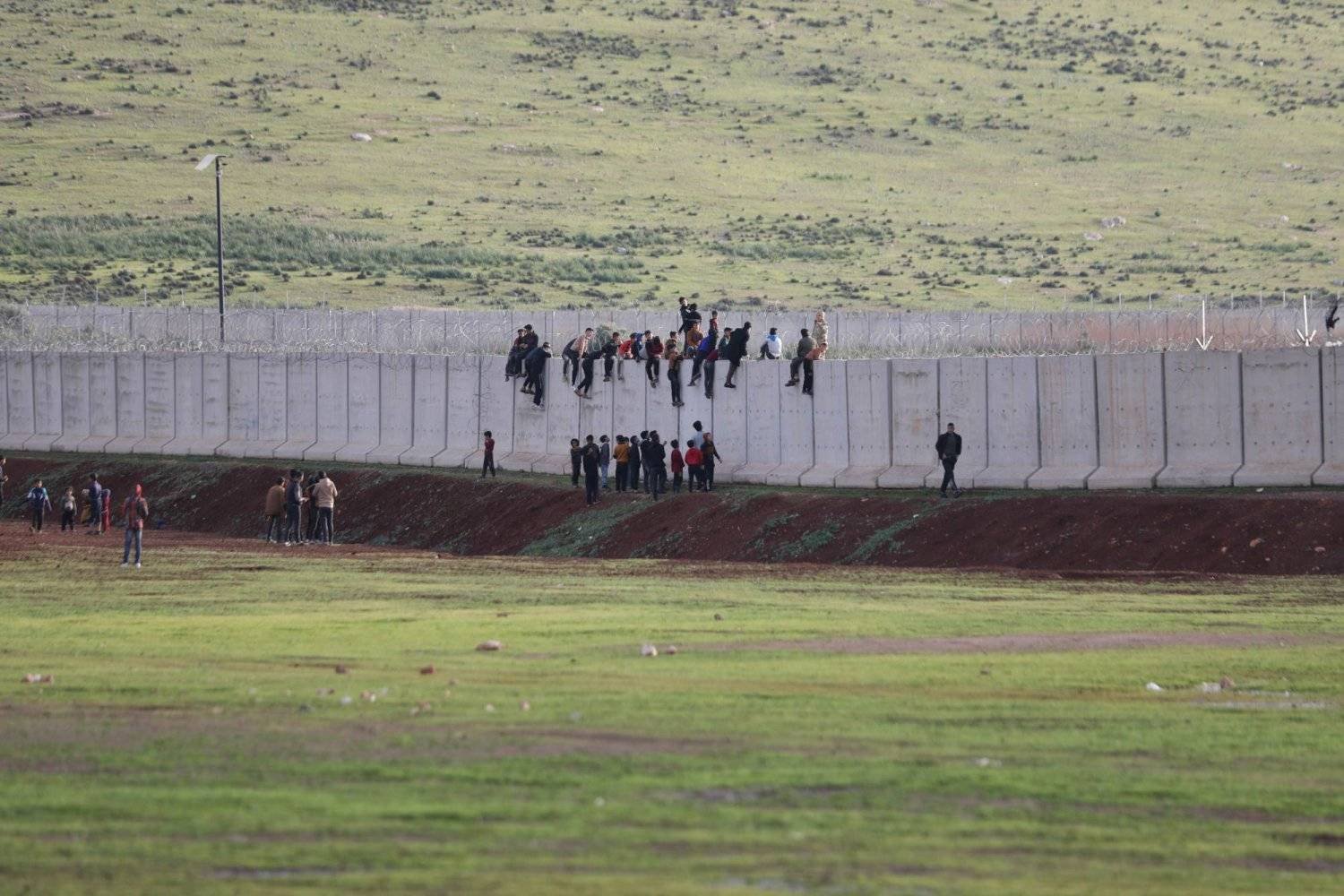 Despite ongoing assaults by Turkish border guards, children still climb to the top of the border wall for recreation (Asharq Al-Awsat)