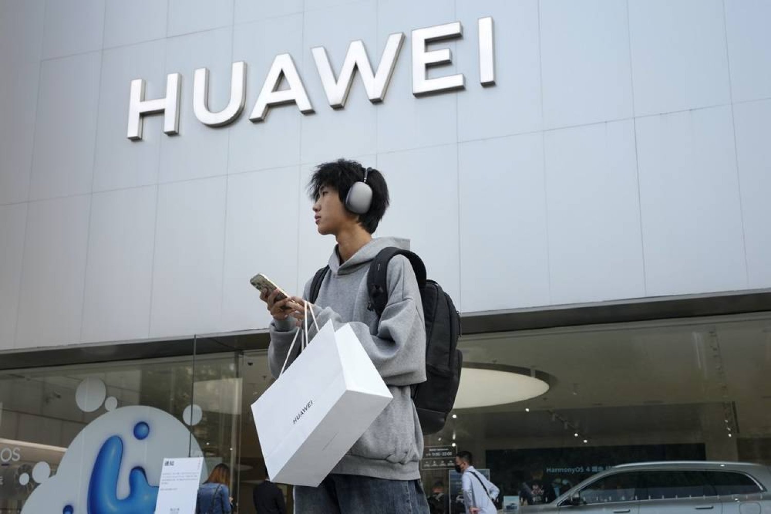 A customer carries his purchased Huawei product outside a Huawei store after he attended the Huawei new product launch conference in Beijing, on Sept. 25, 2023. (AP)
