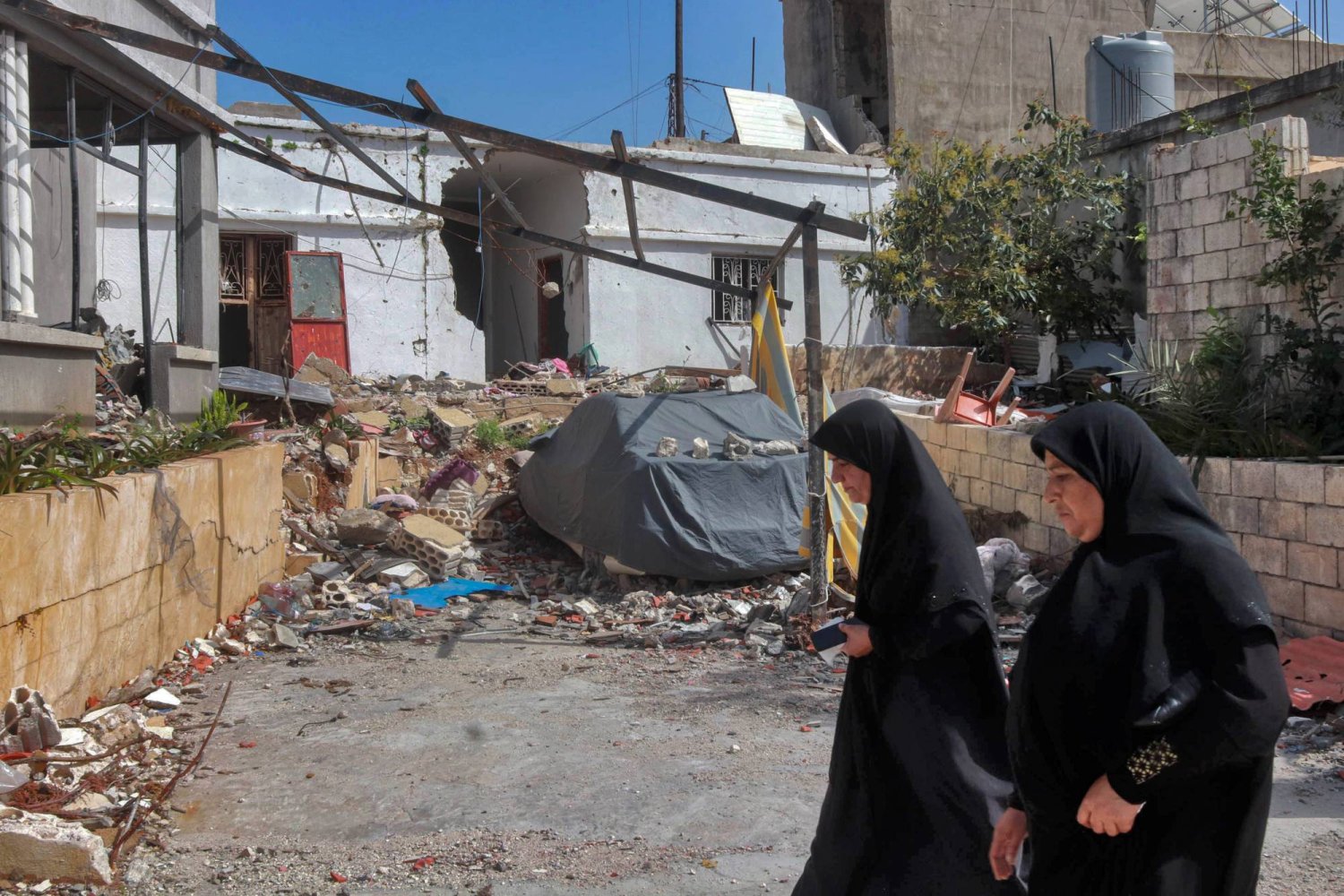28 March 2024, Lebanon, Naqura: Lebanese women walk past rubble of a café that was hit by an overnight Israeli strike in the southern Lebanese village of Naqoura. Photo: STR/dpa