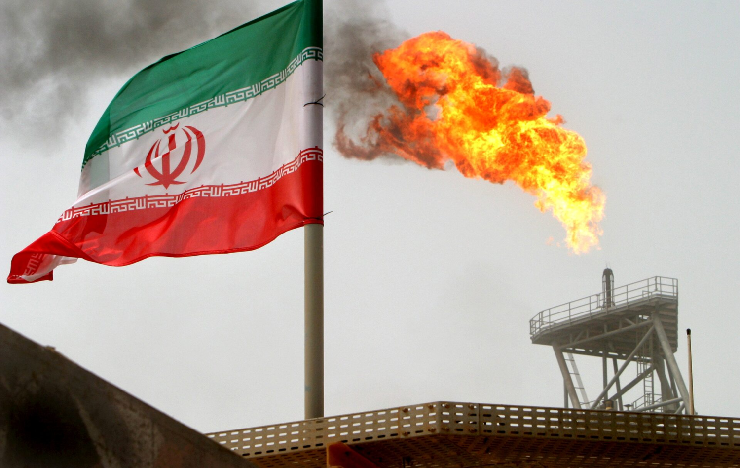 A gas flare on an oil production platform is seen alongside an Iranian flag in the Gulf July 25, 2005. Reuters