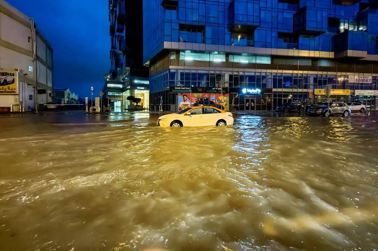 A taxi drives through a flooded street following heavy rains in Dubai early on April 17, 2024. (AFP)