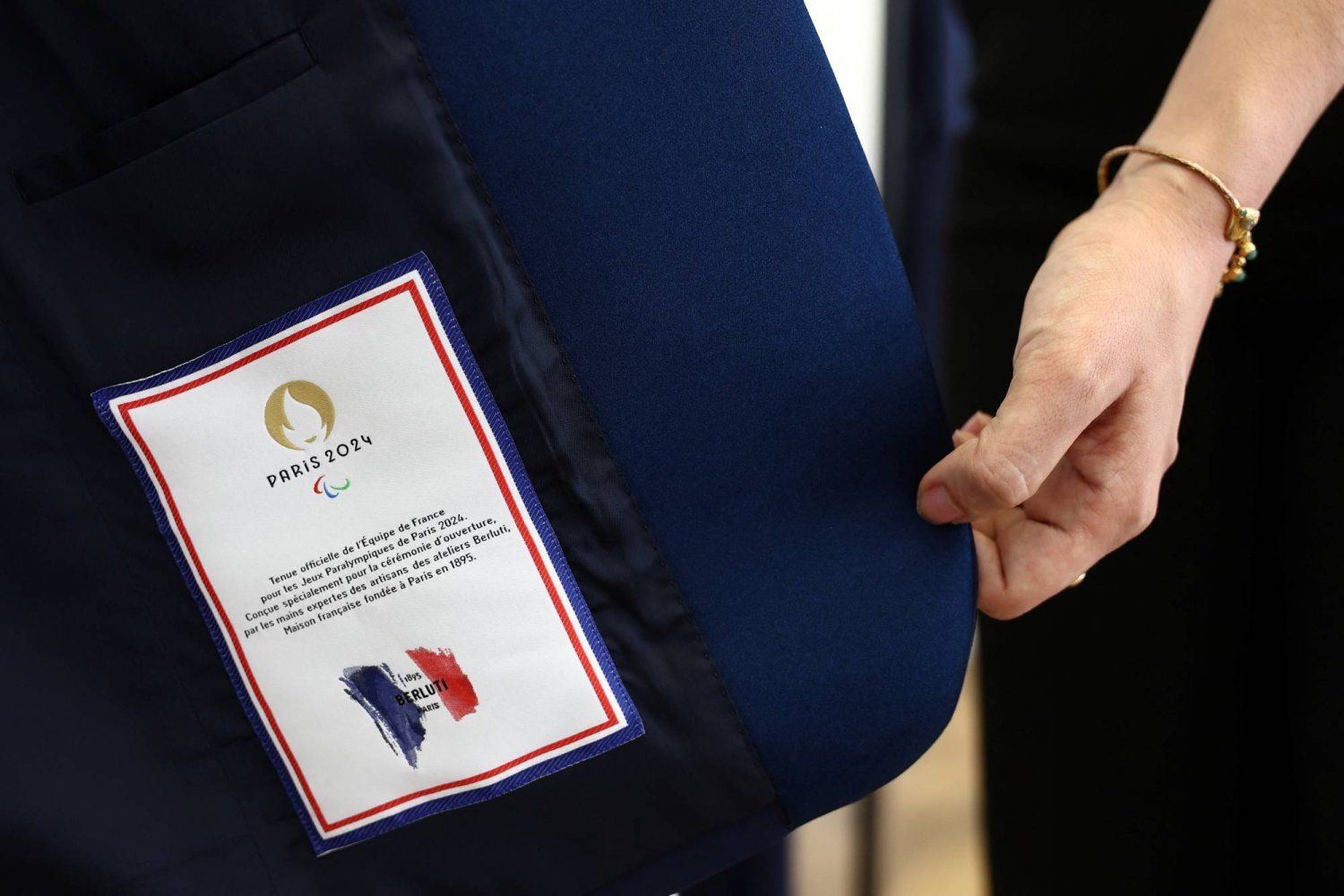 An employee shows the Paris 2024 - Berluti label sewn inside the suit jacket for the French team athletes for the opening ceremony by LVMH's upscale menswear label Berluti, in a showroom at Berluti headquarters in Paris, France, April 10, 2024.  REUTERS/Stephanie Lecocq
