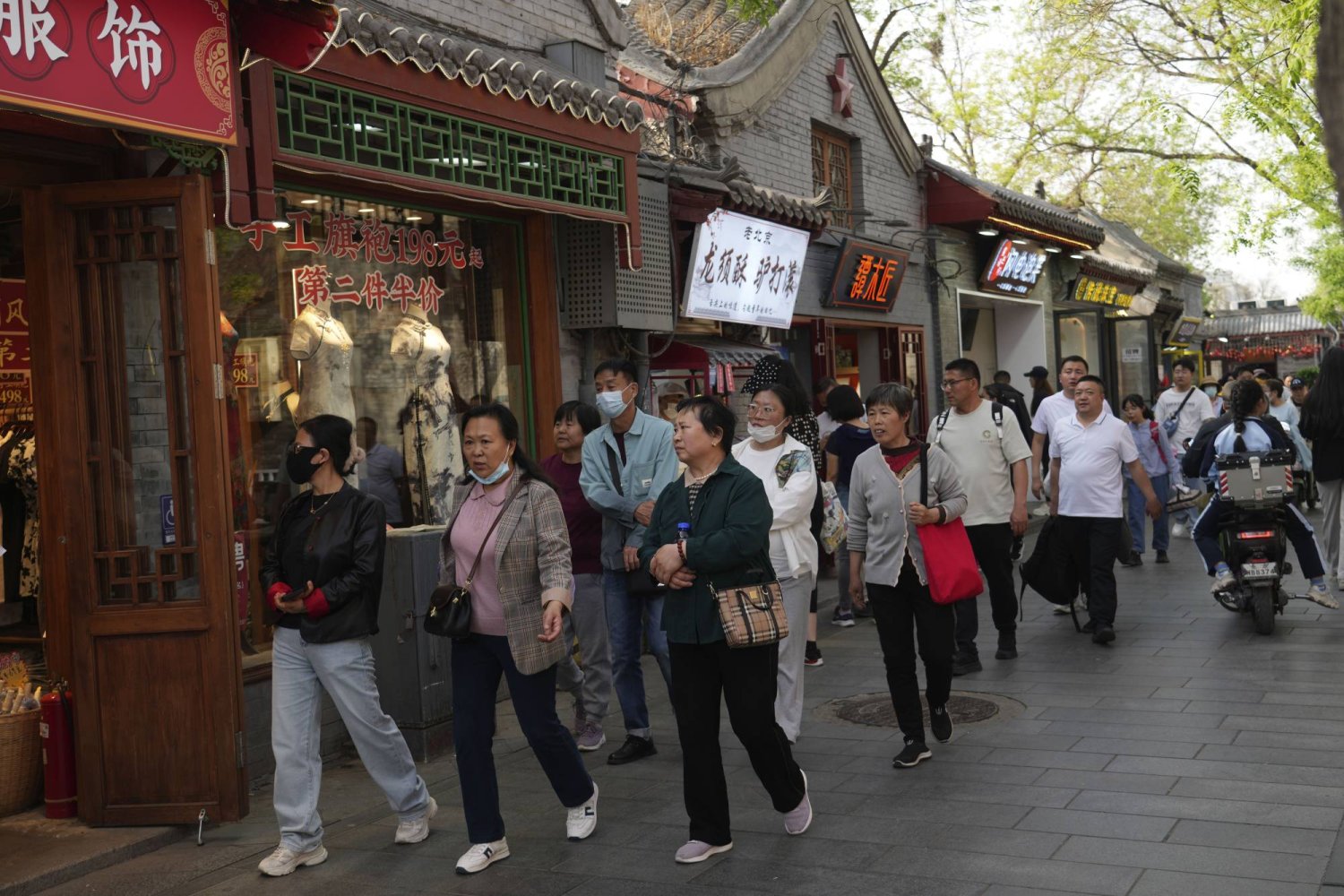 Visitors pass through at the Nanluoguxiang, the capital city's popular tourist spot in Beijing, China, Wednesday, April 17, 2024. (AP Photo/Tatan Syuflana)