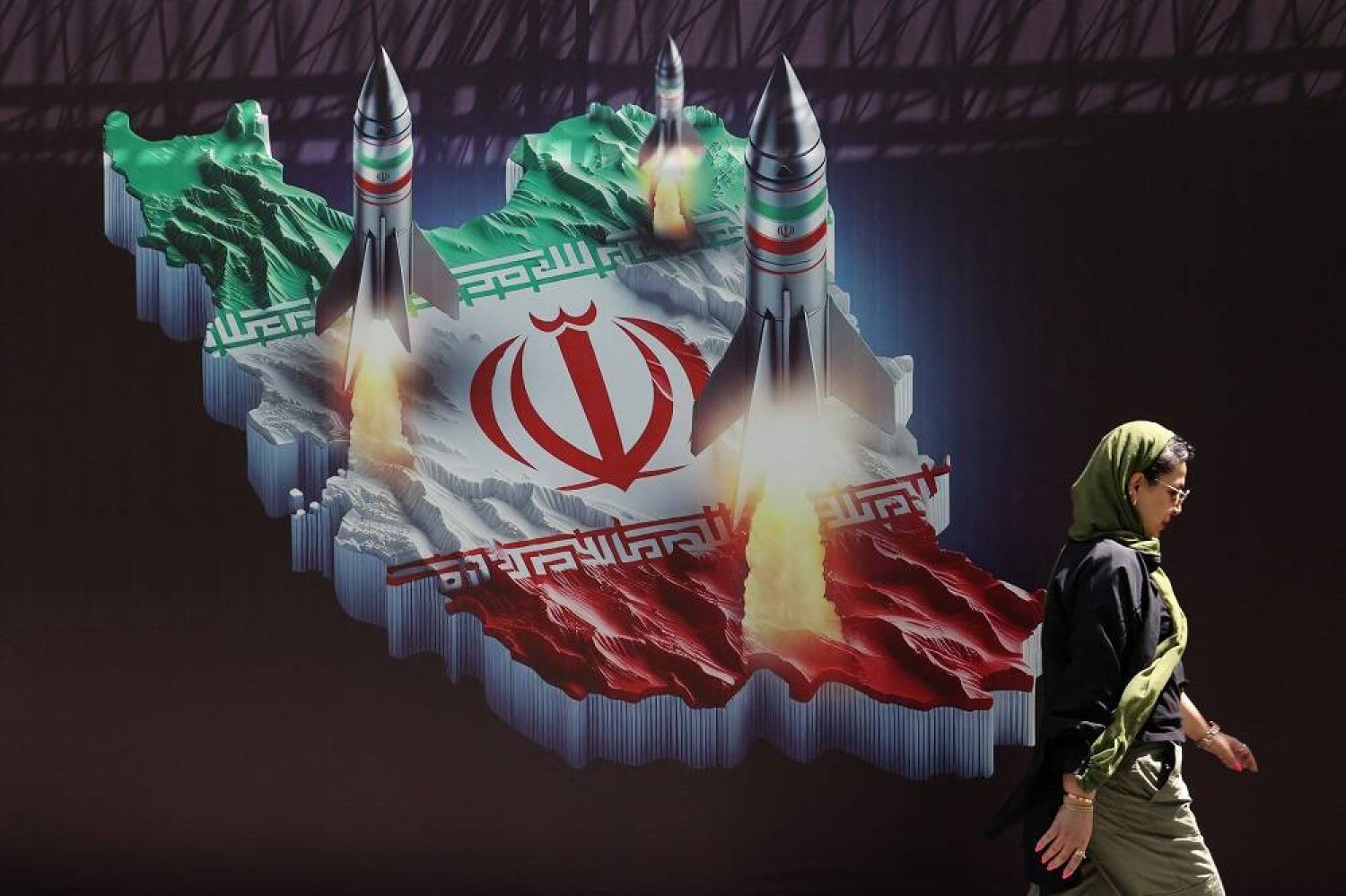 An Iranian woman walks past an anti-Israel banner with a picture of Iranian missiles on a street in Tehran, Iran April 19, 2024. Majid Asgaripour/WANA (West Asia News Agency) via Reuters