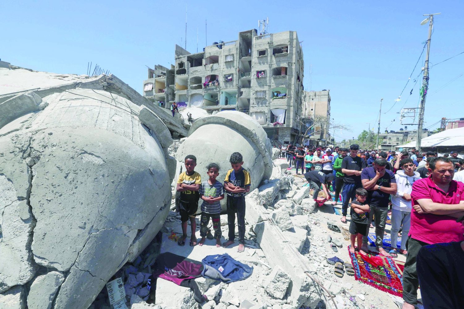 Palestinians perform Friday noon prayer on April 19, 2024, next to the ruins of Al-Farouq Mosque, destroyed during Israeli bombardment in Rafah in the southern Gaza Strip, amid ongoing battles between Israel and the Hamas group. (Photo by MOHAMMED ABED / AFP)
