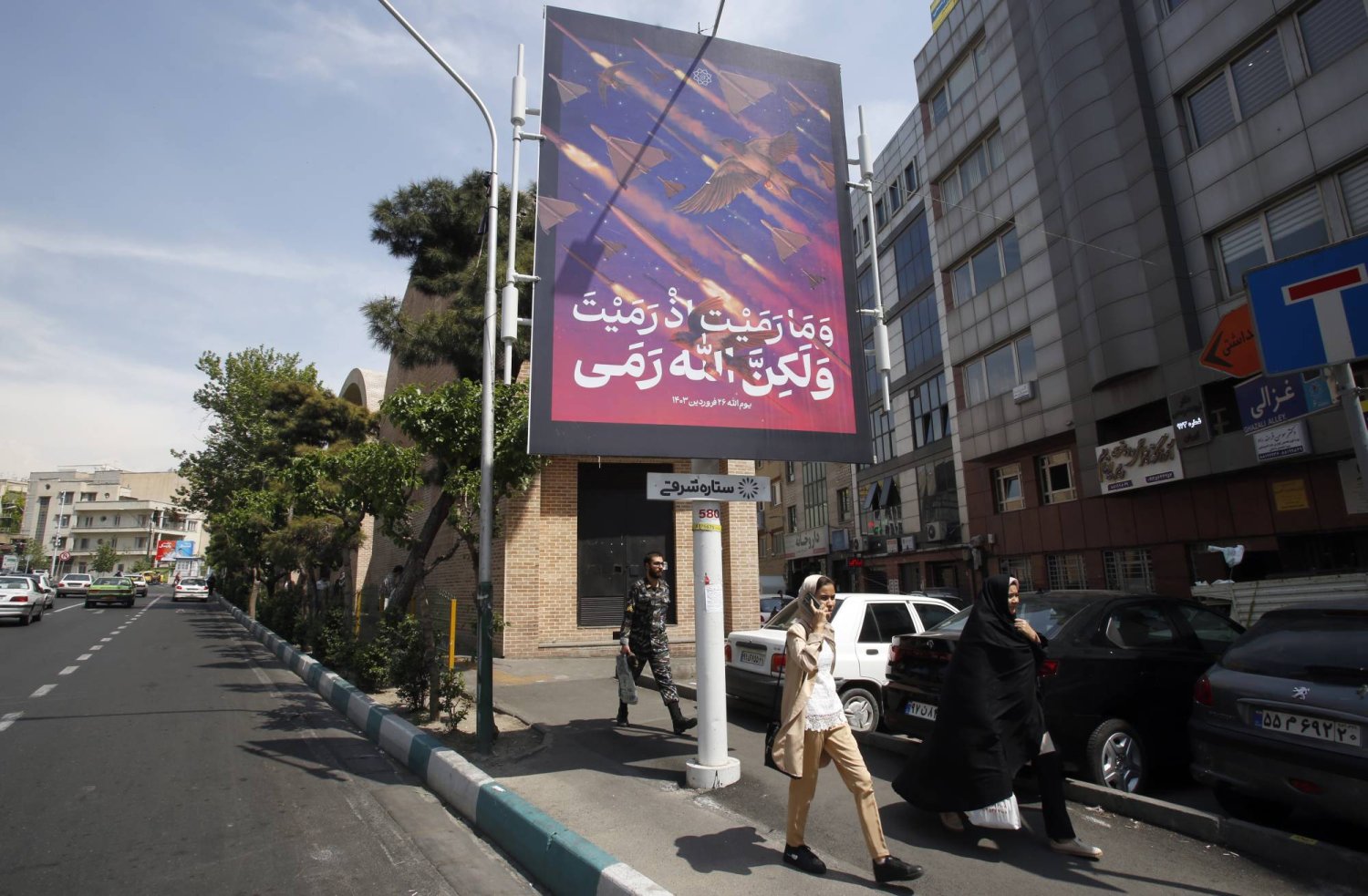 Iranians walk near an anti-Israel banner carrying pictures of Iranian missiles and drones in Tehran, Iran, 22 April 2024. EPA/ABEDIN TAHERKENAREH