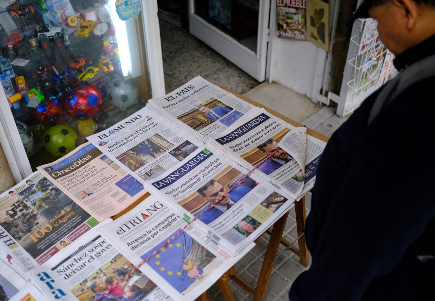A man looks at the front pages of Spanish newspapers reporting Prime Minister Pedro Sanchez's decision to suspend public duties after the court launched a preliminary investigation into his wife Begona Gomez, at a newspaper shop in Barcelona, Spain. REUTERS/Nacho Doce