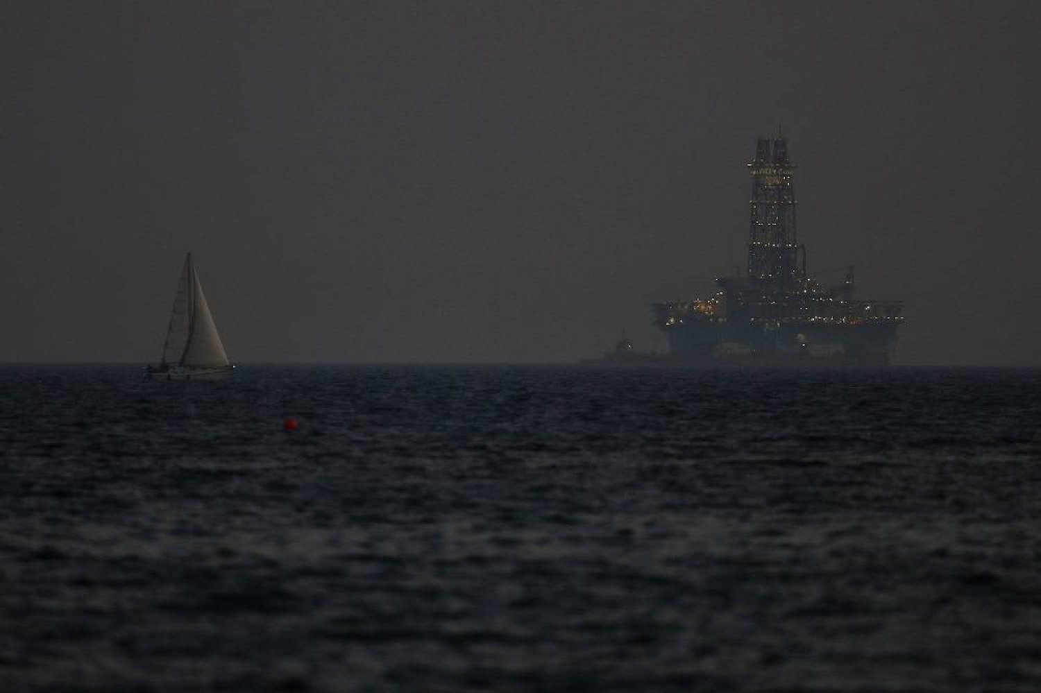 An offshore drilling rig is seen in the waters off Cyprus' coastal city of Limassol, on July 5, 2020 as a sailboat sails in the foreground. (AP)