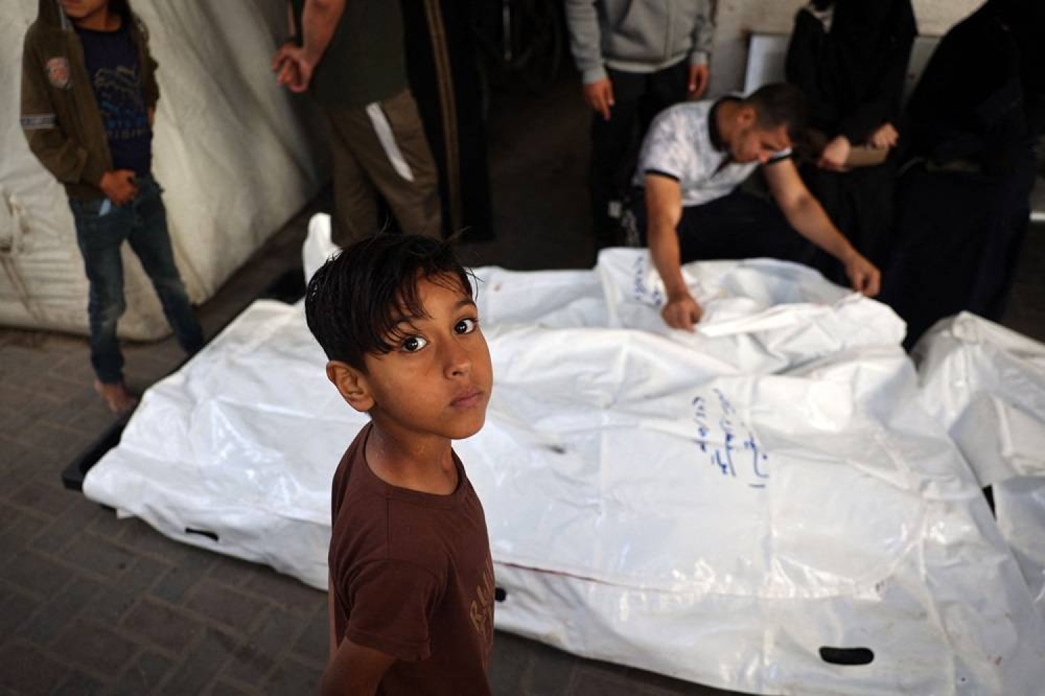 A young boy looks on as relatives of Palestinians killed in Israeli bombing, mourn near their corpses in the yard of the al-Najjar hospital in Rafah in the southern Gaza Strip on May 3, 2024, amid the ongoing conflict between Israel and the Hamas movement. (AFP) 